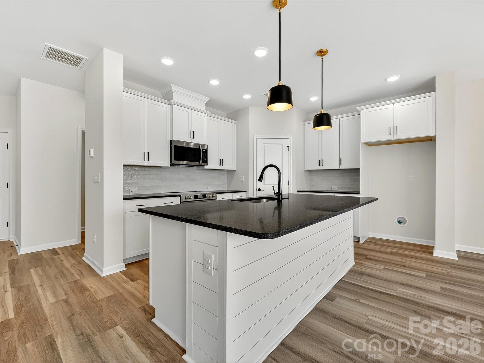 Discover the ease of luxury low-maintenance living in this brand-new Mecklenburg II townhome, conveniently located just minutes from Ballantyne, Waverly, and the charming shops and restaurants of historic downtown Waxhaw. Filled with natural light, the open-concept living area is highlighted by three large picture windows overlooking a private wooded backyard. The designer kitchen features 42” White colored soft-close cabinetry, sleek honed granite countertops, a spacious shiplap wrapped island open to the family room, Frigidaire stainless steel appliances, an exterior-vented range hood, and a pantry with solid shelving. The main level showcases durable LVP flooring throughout, along with composite stair treads leading to the second floor. Upstairs there is a loft area with LVP flooring, unwind in the luxurious Owner’s Retreat featuring a tray ceiling, oversized walk-in closet, and three large windows that create a bright, airy feel. The spa-inspired primary bath offers tiled flooring, a large tiled walk-in shower with bench seating, oversized dual vanity with quartz countertops and soft-close cabinetry, a linen closet, and a private water closet. The second floor also includes two spacious secondary bedrooms, a full hall bath, and a thoughtfully designed laundry room with tiled flooring and a convenient folding table. Enjoy peaceful mornings or relaxing evenings on the covered porch with private backyard. A side-by-side two-car garage and full driveway provide ample parking for both homeowners and guests. With low taxes, low-maintenance living, and the feel of a single-family home, this townhome offers the perfect blend of comfort, convenience, and style. Ask about special low-interest rate opportunities!
