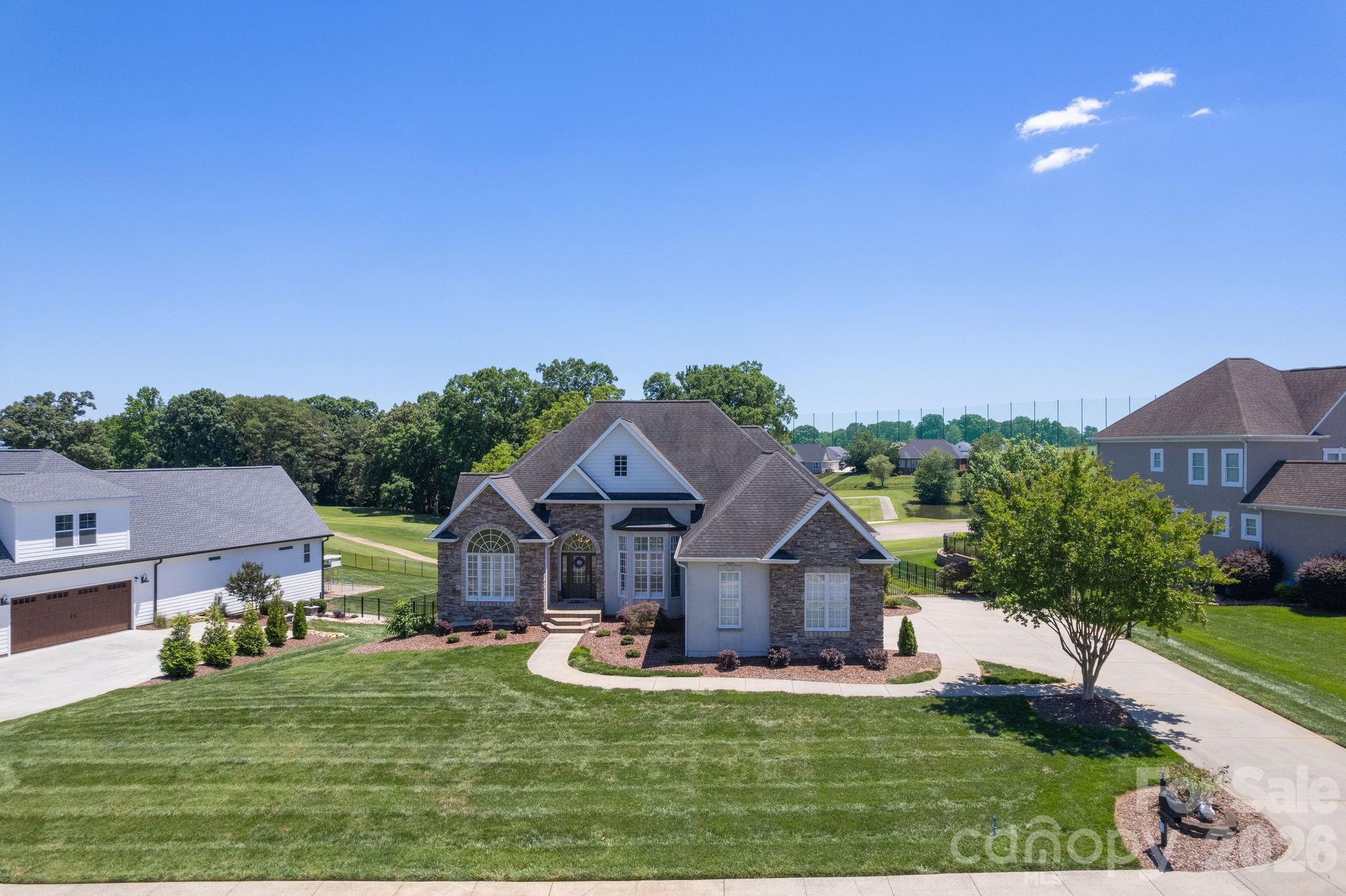 Perched along the 8th fairway of the Deer Brook Golf Course, this stunning 5-bedroom, 3.5-bath estate offers the rare combination of refined living and resort-style serenity, all on over half an acre in one of Shelby's most sought-after communities.
From the moment you arrive, the stone veneer and stucco exterior set a tone of timeless elegance. Inside, soaring volume ceilings and rich hardwood floors carry you through a thoughtfully designed open floor plan, where natural light pours in and fairway views serve as the backdrop to everyday life.
The heart of the home is a show-stopping stone fireplace with gas logs, the kind that anchors a room and invites conversation. The kitchen is equal parts functional and beautiful, featuring stainless appliances, corian countertops, a breakfast bar, a breakfast nook, and a pantry. A formal dining room, private office, and laundry room round out the main level's versatile layout.
The main-level primary suite is a true retreat, featuring a trey ceiling, double vanity, tile walk-in shower, jetted soaking tub, and an oversized walk-in closet. Two additional bedrooms and a full bath also sit on the main floor, ideal for a split-bedroom arrangement that offers privacy for everyone.
Downstairs, the finished basement opens up a world of possibility. A massive game room, two additional bedrooms, and a full bath make it perfect for multigenerational living, hosting guests, or creating the ultimate entertainment space. Two unfinished areas remain ready for your vision.
Step outside to a rear balcony or the lower patio, where the golf course views stretch out before you, the kind of backdrop that makes morning coffee feel like a weekend getaway.
Completing the package: an in-ground irrigation system, double-car garage, and an address that places you in the heart of Deer Brook with easy access to everything the greater Shelby area has to offer.