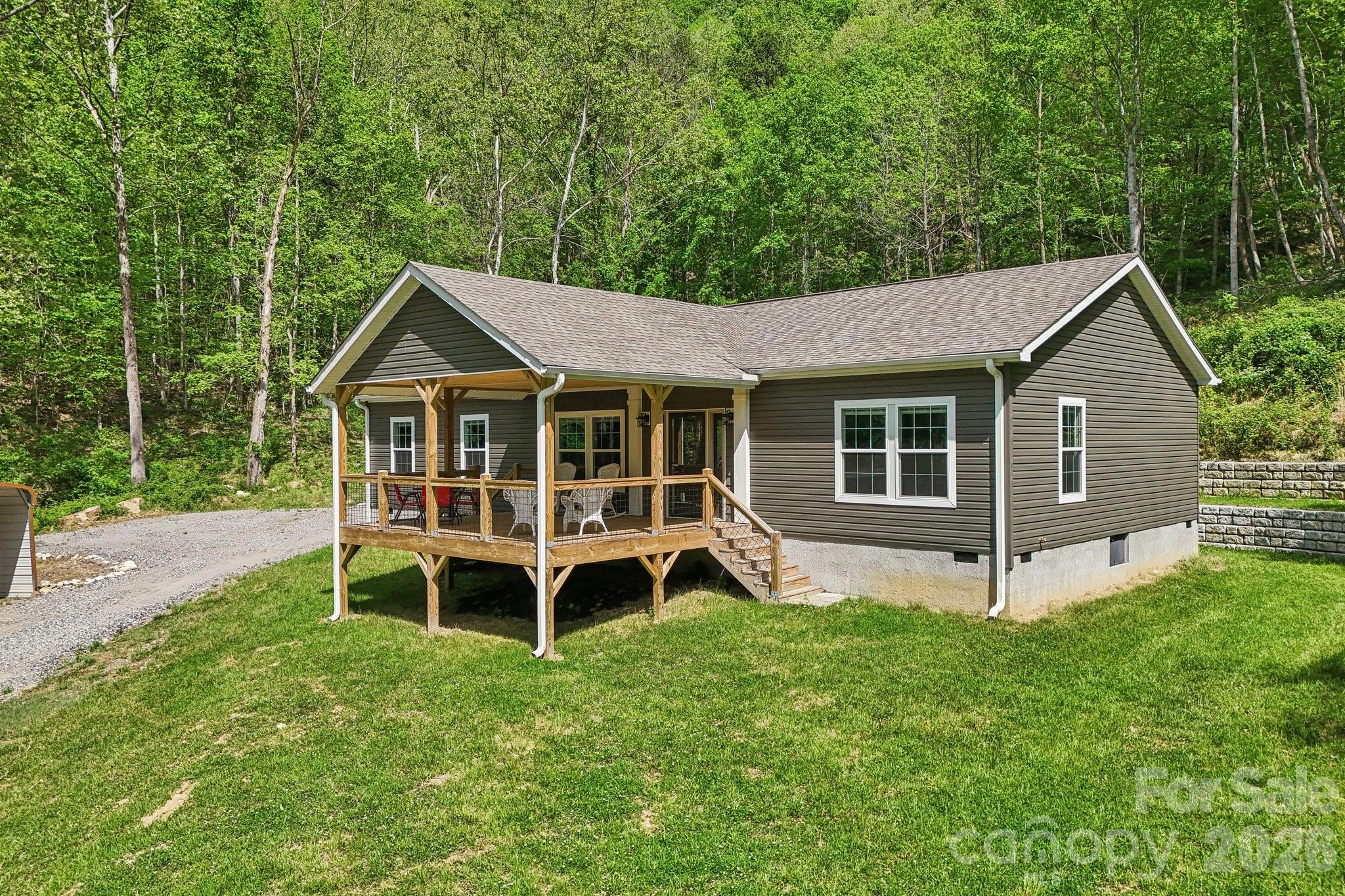 Welcome to your own private mountain retreat and get far more than you might expect, where comfort, beauty, and possibility come together across 76± acres of stunning hardwood forest. Tucked away yet just 25 miles from Asheville, this thoughtfully designed home with underground power on a concrete pad offers a rare blend of peaceful seclusion and everyday convenience. 

Step inside to find a warm, inviting interior with 9-foot ceilings and an open floor plan that feels both spacious and cozy. The heart of the home is the great room, flowing effortlessly onto an oversized covered porch—perfect for enjoying quiet mornings, evening sunsets, and the surrounding natural beauty. The kitchen is equally inviting, featuring stainless steel appliances, generous counter and cabinet space, and a charming butler’s pantry for added functionality.

The primary suite is a true retreat, complete with dual walk-in closets, a soaking tub, and a separate walk-in shower—creating a spa-like space to unwind. A split-bedroom layout offers privacy, with two additional bedrooms and a full bath ready to welcome family or guests.

Outdoors, the land invites exploration and opportunity, with miles of trails I have enjoyed traveling on a side by side, multiple potential homesites with breathtaking views, and valuable hardwoods that can be harvested or sold. Enjoy the abundant wildlife including deer, bear and turkey. Make use of the natural springs that originate on the property. A tractor shed and additional outbuilding add even more flexibility for hobbies, storage, or outdoor pursuits. This peaceful cove would also make a wonderful place to set up multiple glamping sites or tiny homes for a woodland retreat! You might consider making use of the forestry program saving $$ on taxes.

Whether you're seeking a peaceful full-time residence, a family getaway, or land with long-term potential, this property offers a truly special place to call home.

If you are looking for additional income, there is a large portion of the woods that is ripe for timbering!