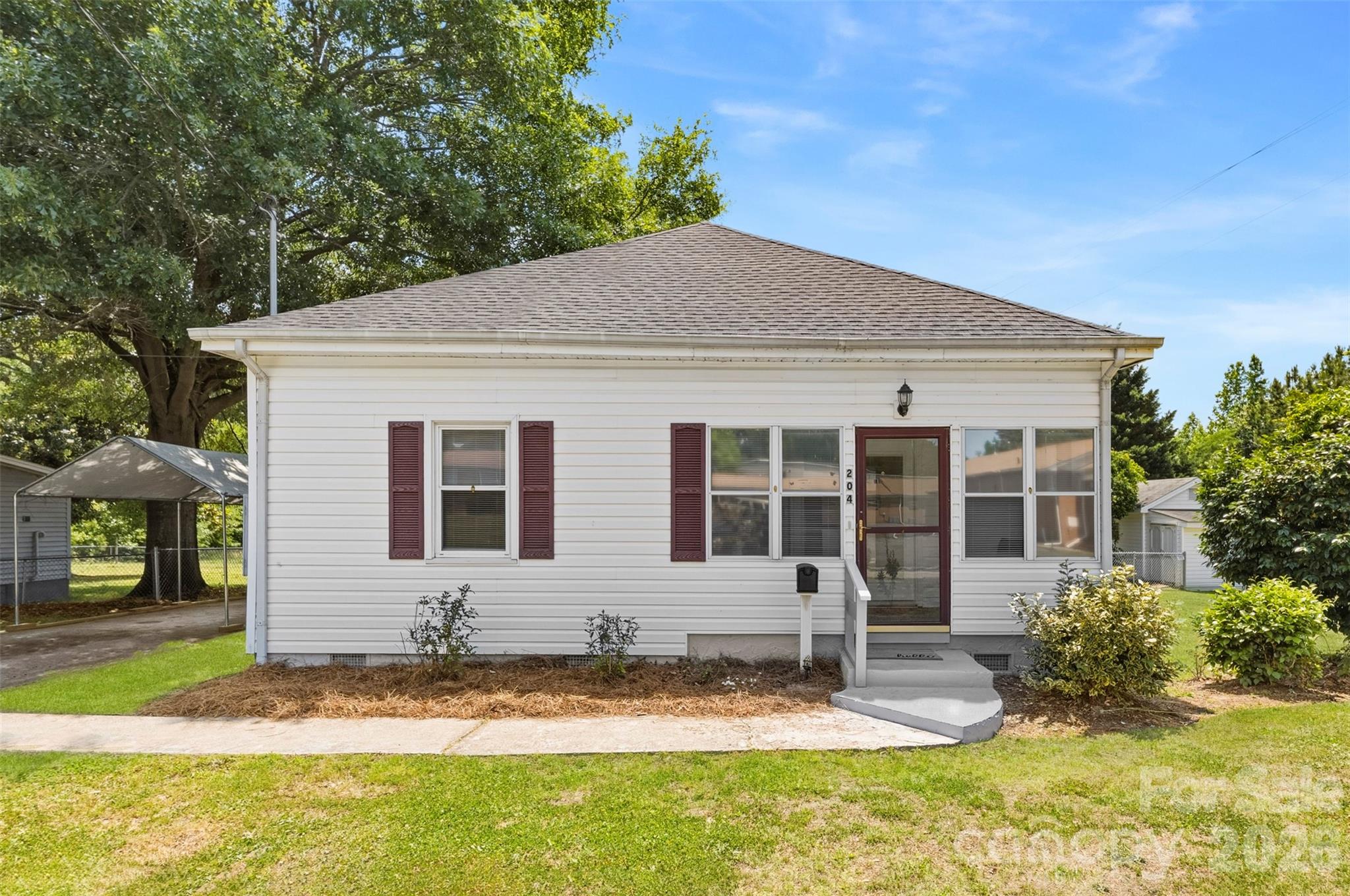Charming one-level home situated on a spacious corner lot in the heart of Clover! This 2-bedroom, 1.5-bath home offers a functional layout with plenty of natural light and comfortable living spaces throughout. The large kitchen features abundant cabinet and countertop space, a center island with seating, and room for gathering. A new refrigerator that will convey with the sale of the home. All appliances will convey including washer and dryer, dishwasher, stove, and microwave. There is a large laundry room on the back of the home. Enjoy relaxing on the inviting screened-in front porch or spending time in the expansive backyard with plenty of room for outdoor activities, gardening, or entertaining. For parking, there is a covering used as a carport. A 12x24 ft wired workshop/outbuilding provides the perfect space for hobbies, storage, an office, or additional projects. Recent updates to the home include a new roof and chain link fence in 2025, freshly painted in the interior, new ceiling fans, new plumbing in kitchen sink, and added insulation in the crawlspace. A whole house attic fan and extra storage room in the attic. The seller is offering a 1-year home warranty to the next buyer. The home is conveniently located within walking distance to downtown Clover, shopping, dining, and schools, this property combines small-town charm with everyday convenience