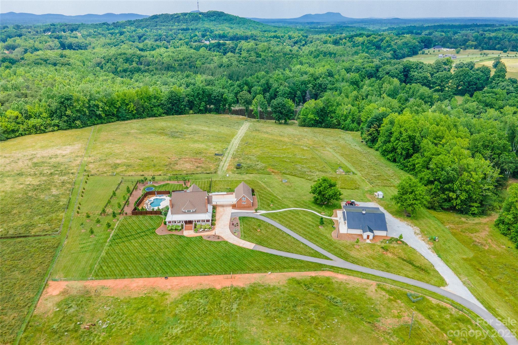 Ready to move in and bring the horses! Incredible opportunity to own a farmhouse with too many features to name. Beautifully designed with a welcoming wrap around porch. Great entertaining home offers dramatic ceilings with exposed woods beams and southern charm. The gourmet kitchen is quite impressive and has all the bells and whistles! The resort-like outdoor oasis features an in-ground gunite pool (heated) with grotto, gorgeous fireplace & travertine tile patio is covered with built in heaters which is the perfect spot for all four seasons. Outdoor play time made complete with an in-ground trampoline! Stocked pond for fishing. 55x55 Barn is wired with 4 stalls, two separate restrooms & has great potential for hosting events or weddings.Recent updates: Travertine tile, upgraded HVAC, patio extension, metal roofing, closed cell foam insulation in barn walls/ceiling, additional 2 stall barn. This home is ready for its new owners. Includes Tract B&C Adjoining properties.