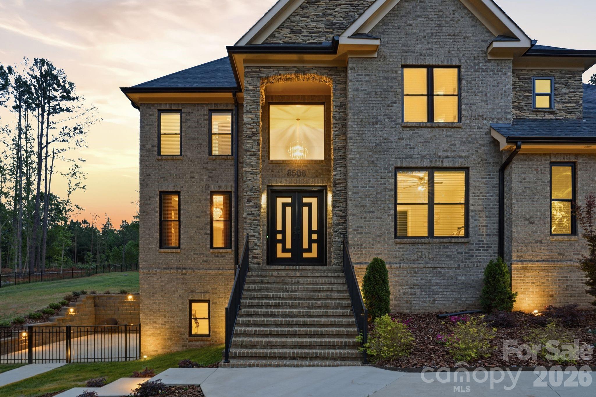 Set on 1.14 private acres, this beautifully designed home offers the perfect balance of space, comfort, and everyday luxury. As you arrive, the setting immediately feels private and peaceful, welcoming you into a home that’s both functional and inviting.

Step inside to a grand staircase entry filled with natural light, creating a bright and open first impression. To the right, the main living area flows effortlessly into the breakfast space and kitchen, making it ideal for both daily living and entertaining. The kitchen is thoughtfully designed with a custom farmhouse sink with exposed apron detail, built-in double wall ovens, and two statement chandeliers that add warmth and character. The living room is centered around a dramatic floor-to-ceiling fireplace with a sleek linear insert and custom panel detailing, creating a standout focal point.

The dining room offers a more intimate setting, featuring a custom accent wall with integrated lighting and a designer chandelier that brings a sense of style and comfort to the space. The main level also includes a bedroom with its own bathroom, along with an additional guest bath, providing flexibility for visitors or multi-use living.

Upstairs, the primary suite is designed as a private retreat, featuring a custom media accent wall and a clean, modern feel. The primary bathroom includes a double floating vanity, freestanding soaking tub, and a glass-enclosed shower with warm, designer finishes throughout. Three additional bedrooms, a full bathroom, and an upstairs laundry room complete the second level, offering both convenience and functionality.

The fully finished basement expands the home’s living space and creates an ideal setup for entertaining. A custom built-in bar with seating and wine storage opens directly to the outdoor patio through elegant double glass doors, creating a seamless blend of indoor and outdoor living. The media lounge features a built-in wall with shelving and a sleek fireplace, perfect for relaxing evenings. This level also includes an additional den area, a large storage closet, and a full bathroom.

Outside, the property continues to impress with a detached 24x24 outbuilding that can be used as a gym, office, studio, or entertainment space. The expansive yard offers endless possibilities to create your own private outdoor setup.

With 4,316 heated square feet, 5 bedrooms, 4.5 bathrooms, and a layout designed for both everyday living and hosting, this home offers a lifestyle that adapts to you—whether you're entertaining, working from home, or simply enjoying the space and privacy.
