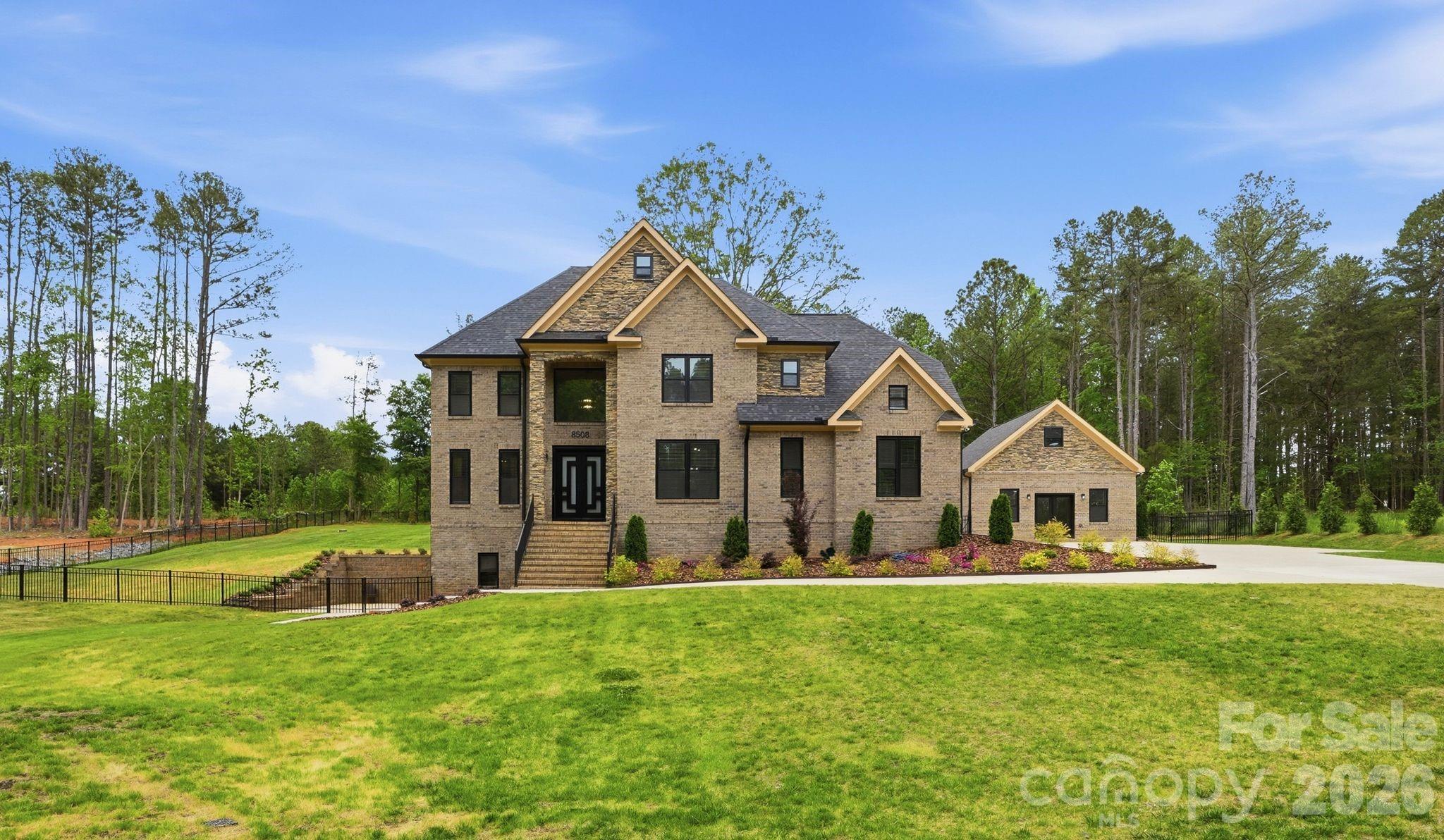 Set on 1.14 private acres, this beautifully designed home offers the perfect balance of space, comfort, and everyday luxury. As you arrive, the setting immediately feels private and peaceful, welcoming you into a home that’s both functional and inviting.

Step inside to a grand staircase entry filled with natural light, creating a bright and open first impression. To the right, the main living area flows effortlessly into the breakfast space and kitchen, making it ideal for both daily living and entertaining. The kitchen is thoughtfully designed with a custom farmhouse sink with exposed apron detail, built-in double wall ovens, and two statement chandeliers that add warmth and character. The living room is centered around a dramatic floor-to-ceiling fireplace with a sleek linear insert and custom panel detailing, creating a standout focal point.

The dining room offers a more intimate setting, featuring a custom accent wall with integrated lighting and a designer chandelier that brings a sense of style and comfort to the space. The main level also includes a bedroom with its own bathroom, along with an additional guest bath, providing flexibility for visitors or multi-use living.

Upstairs, the primary suite is designed as a private retreat, featuring a custom media accent wall and a clean, modern feel. The primary bathroom includes a double floating vanity, freestanding soaking tub, and a glass-enclosed shower with warm, designer finishes throughout. Three additional bedrooms, a full bathroom, and an upstairs laundry room complete the second level, offering both convenience and functionality.

The fully finished basement expands the home’s living space and creates an ideal setup for entertaining. A custom built-in bar with seating and wine storage opens directly to the outdoor patio through elegant double glass doors, creating a seamless blend of indoor and outdoor living. The media lounge features a built-in wall with shelving and a sleek fireplace, perfect for relaxing evenings. This level also includes an additional den area, a large storage closet, and a full bathroom.

Outside, the property continues to impress with a detached 24x24 outbuilding that can be used as a gym, office, studio, or entertainment space. The expansive yard offers endless possibilities to create your own private outdoor setup.

With 4,316 heated square feet, 5 bedrooms, 4.5 bathrooms, and a layout designed for both everyday living and hosting, this home offers a lifestyle that adapts to you—whether you're entertaining, working from home, or simply enjoying the space and privacy.