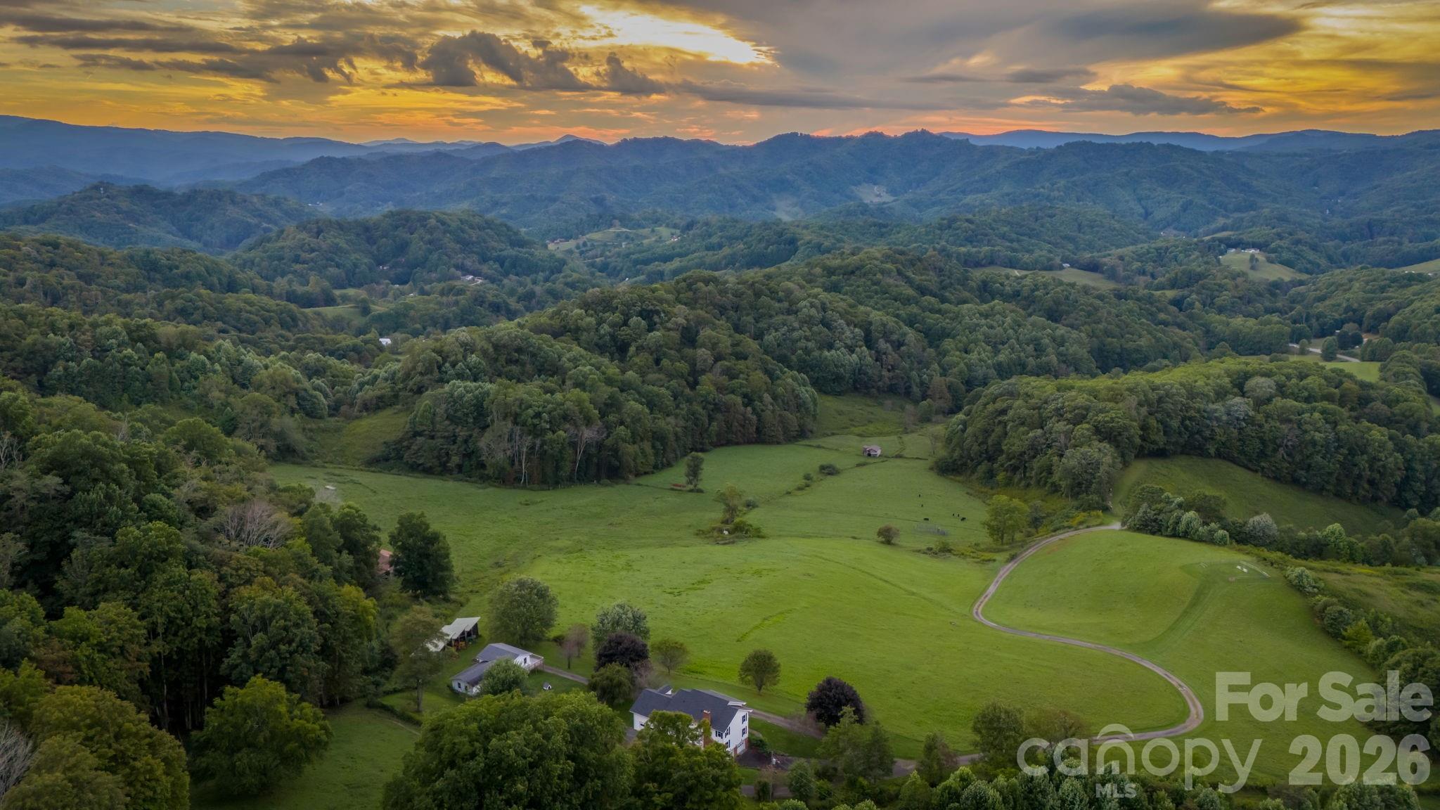 Apple Tree Farm - a rare offering of 240+ acres with a farmhouse, unfinished garage/building, storage building, two barns, and trails - with wooded acreage, sprawling pastures, and long-range, layered Blue Ridge Mountain views at high elevations. With the potential for many different uses, this is the perfect spot for a homestead, family estate/legacy property, horse property, working farm with farming opportunities, or investment opportunity with potential for development - no zoning and no restrictions! Offering easy access year-round from state-maintained roads, this property is just 15 minutes from Appalachian State University and amenities in Boone but offers ample privacy. The large farmhouse front porch is the perfect place for overlooking the green pastures, small pond, and mountains beyond - enjoy mother nature at her finest with acres and acres made for exploring and enjoying the cool Blue Ridge Mountain air! The 3 BR, 2.5 BA home, awaiting the right buyer to put their own personal touches, offers a living room, den, kitchen, and dining room on the first level - upstairs, find a large primary suite, two additional bedrooms, a full bath, and multiple bonus rooms. Additional features: central vacuum, recently replaced windows throughout, wormy chestnut kitchen cabinets, four garage bays, full basement with bathroom, high-speed internet. The farmhouse would also make a great guest home, with the opportunity to build on the acreage! The unfinished garage/building was originally intended as a garage with an apartment above and offers four additional garage bays. An open-air storage building is great for equipment or vehicle storage, and a large usable barn offers even more potential. Apple trees & wildflowers surround the farmhouse and a trail system runs through parts of the wooded acreage to pasture areas. The serenity of Apple Tree Farm lasts year-round with pastoral and sunset views overlooking the majestic Blue Ridge Mountains!