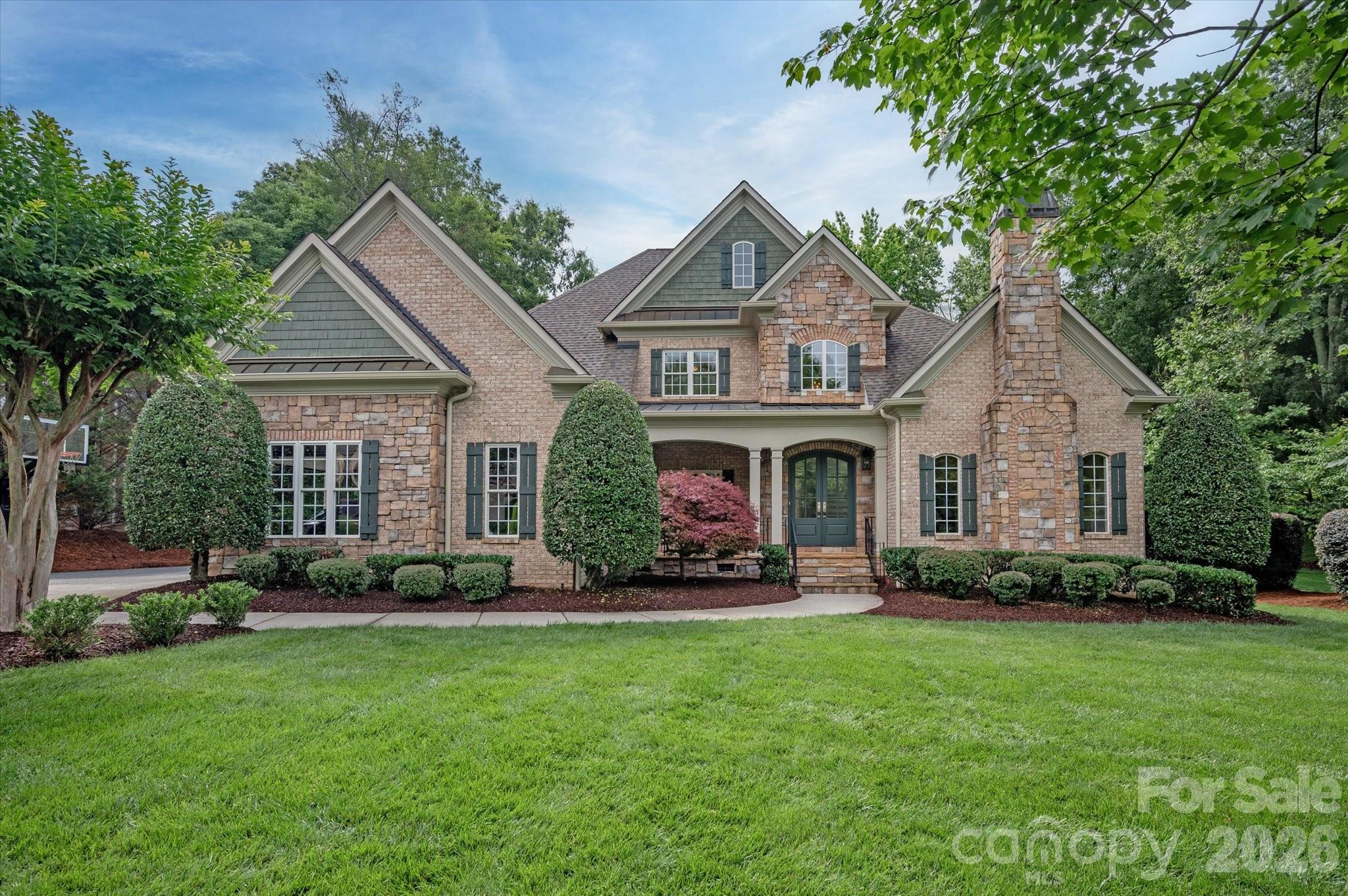Set behind the main gates of Providence Downs, one of Marvin's most sought-after communities, this custom home is positioned on a cul-de-sac lot overlooking a community pond. Thoughtful design and quality craftsmanship create spaces that are both functional and welcoming. The main level features a dedicated office, formal dining room, and a spacious great room filled with natural light, highlighted by a fireplace and custom built-ins. The kitchen opens to the breakfast area, creating a comfortable space for everyday living. The main-level primary suite includes a sitting area, spacious bath, and walk-in closet. Upstairs, four secondary bedroom suites each offer a private bath, along with a large bonus room and large walk-in attic storage. A screened porch and stone terrace overlook the landscaped backyard and pond, while a bridge invites you to the water's edge. The setting offers a beautiful view with privacy. 3 car, side load garage. Enjoy community amenities including a clubhouse, fitness center, swimming pool, tennis and sport courts, playground, and walking trails. Conveniently located near top-rated Marvin schools, shopping & dining.