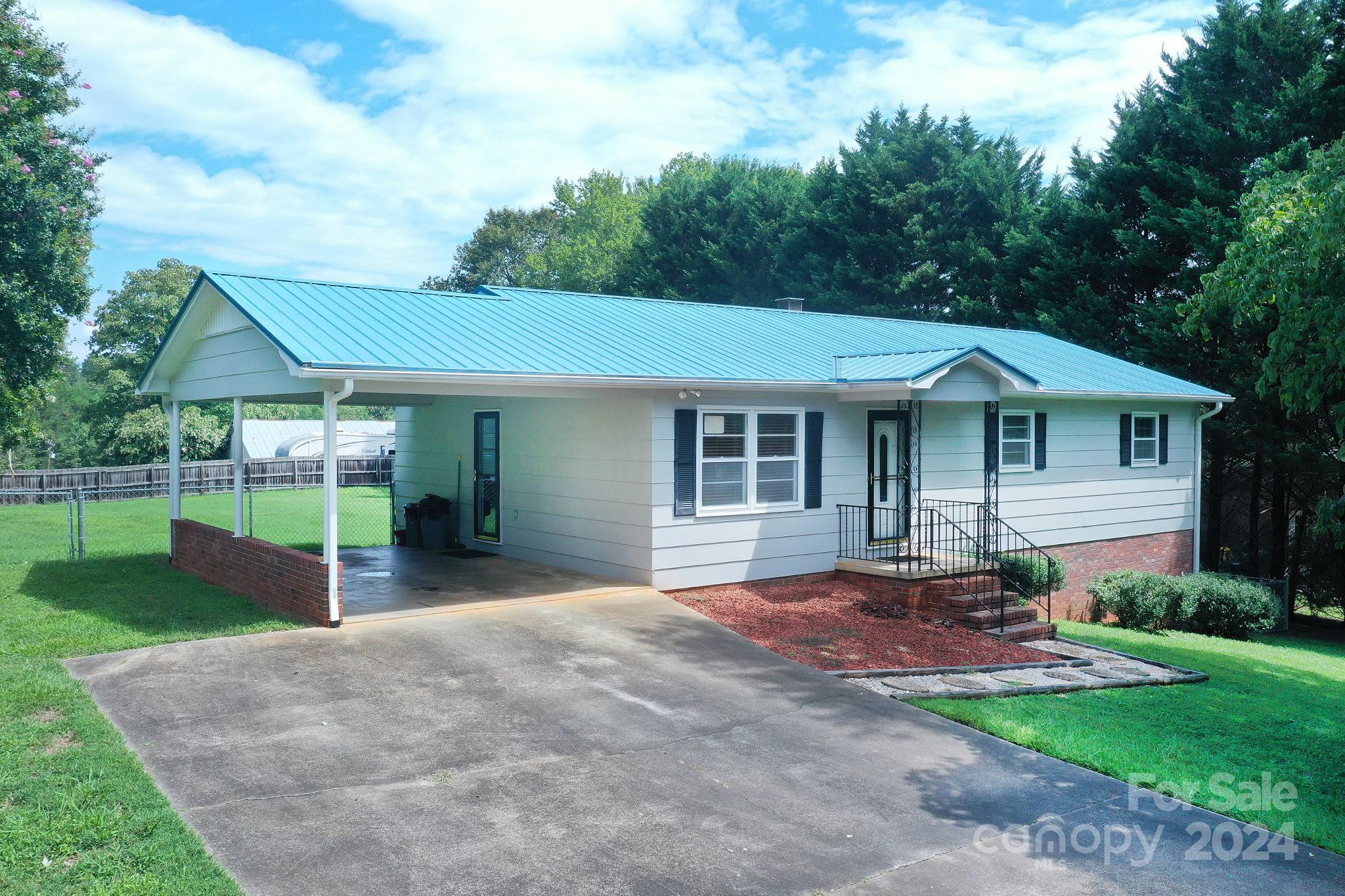 This move-in-ready home features 3 bedrooms, 1.5 baths, and sits on a spacious lot with mature trees and a fenced backyard. It offers a recently updated heat pump, a durable metal roof, and a modern walk-in tiled shower. The full basement is partially finished, providing a versatile workspace and additional space for various needs. Enjoy evenings on the patio, accessible from the walkout basement, and savor the charm of country living without the burden of city taxes.