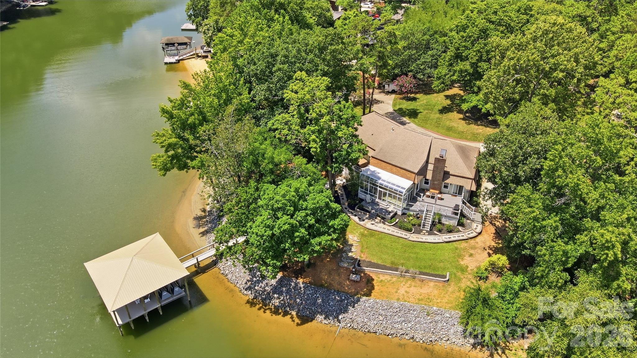 Sprawling waterfront ranch perfectly positioned on one of the largest, most gently sloping lakefront lots on the Tega Cay peninsula. Offering an exceptional setting with easy access to the water, this rare property combines expansive outdoor space, breathtaking lake views, and the ultimate Lake Wylie lifestyle. A bright, welcoming foyer opens to expansive living spaces thoughtfully designed for both everyday living and entertaining. The spectacular great room features dramatic arched windows that frame breathtaking lake views and fill the home with an abundance of natural light.  The kitchen features stainless steel appliances, granite countertops, a center island, and flows seamlessly into the dining room with a cozy fireplace. Just beyond, the inviting sunroom is the perfect place to enjoy your morning coffee, unwind with a good book, or simply take in the panoramic water views. The spacious primary suite offers access to the deck and hot tub, a large walk-in closet, 2 separate vanities, a soaking tub, and an oversized walk-in shower. Two additional bedrooms provide comfortable accommodations for family or guests. Outdoor living is truly exceptional with two expansive Trex covered decks, a hot tub, and beautifully landscaped grounds.  A recently built  covered dock with boat lift,  2 jet ski lifts, and large seating area provides direct access to Lake Wylie for boating, fishing, and endless waterfront recreation. Additional highlights include an oversized two-car garage, circular driveway, and abundant parking. 
Located in the highly sought-after Tega Cay community with nearby golf, tennis, swimming, parks, ball fields, and walking trails. No HOA and situated within the award-winning Fort Mill School District, this rare level waterfront property offers an incredible opportunity to enjoy the very best of Lake Wylie living.