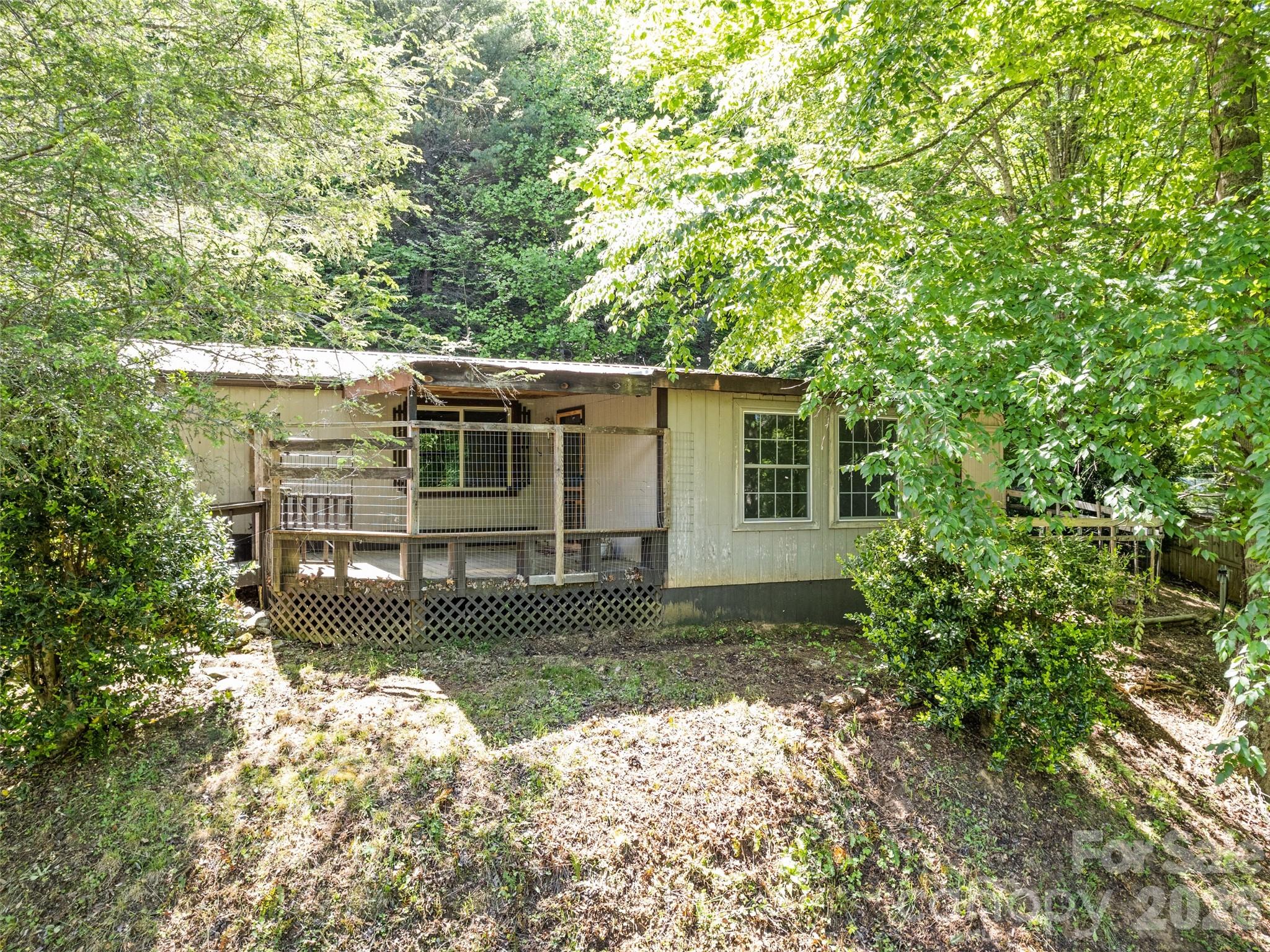 Tucked in the Fines Creek community, this well-maintained and thoughtfully updated 1984 doublewide offers the perfect blend of privacy and comfort on 2.15± unrestricted acres. Take in long range Smoky Mountain views from the sunroom. Designed for easy living, the home features 2 bedrooms, 2 baths, and a versatile views from the sunroom. Designed for easy living, the home features 2 bedrooms, 2 baths, and a versatile flowering plants, and ample space for gardening, entertaining, or simply relaxing in nature. Two powered outbuildings (18’x18’ and 14’x40’) provide exceptional space for hobbies, storage, or a workshop. With year-round access and just 3 miles to I-40, you’re minutes from Waynesville and Asheville. Seek out your serenity here.