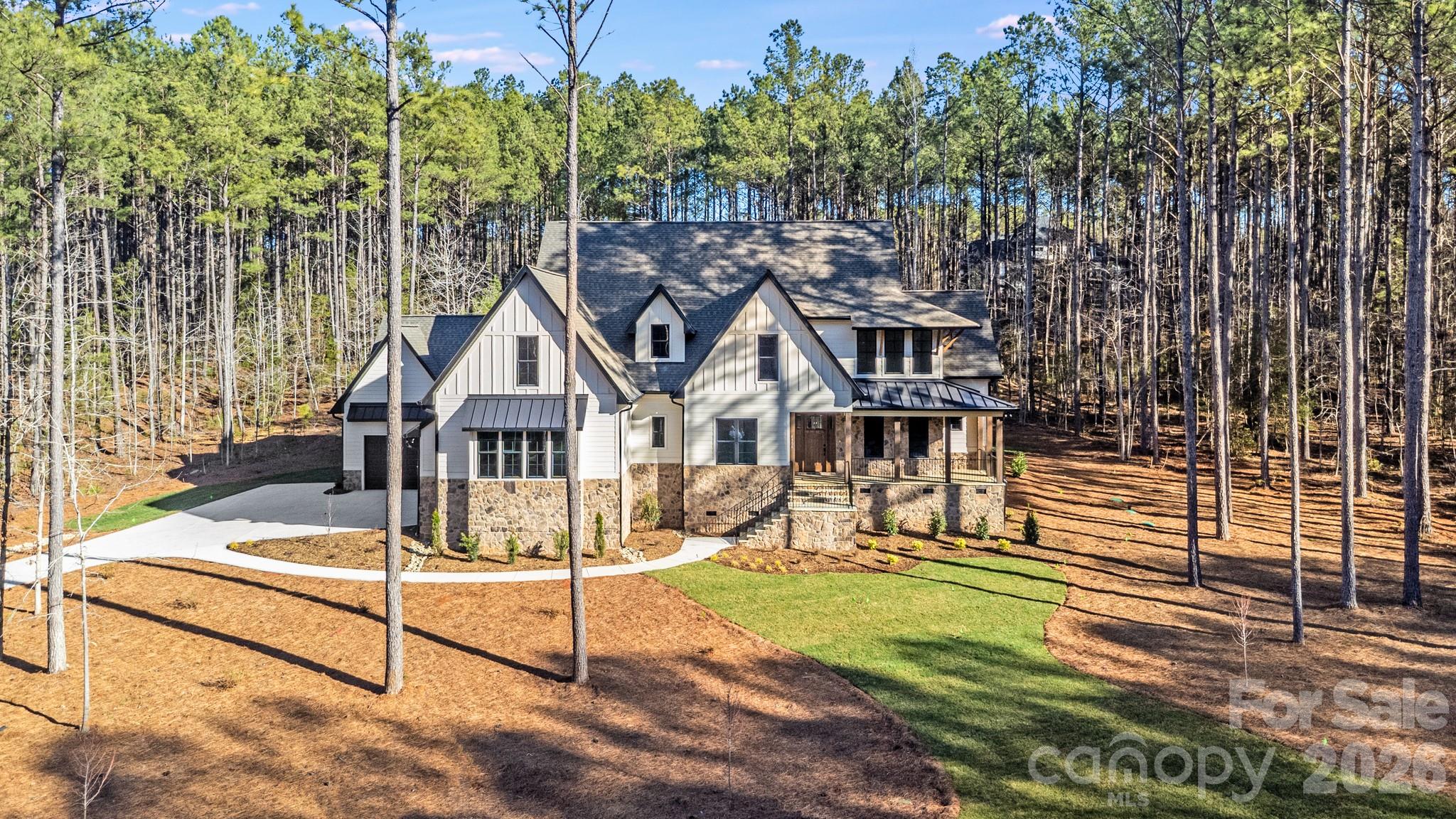 Discover luxury living in this architecturally stunning custom home nestled on 1.63 private wooded acres within the gated community of Riverchase Estates. Offering 4,657 square feet of thoughtfully designed living space, this 5-bedroom, 4.5-bath residence is one of the largest completed homes available in the community.

The dramatic two-story great room features a wall of sliding glass doors that open to a vaulted screened porch with a stone fireplace, creating seamless indoor-outdoor living and the perfect setting for year-round entertaining. The gourmet kitchen showcases premium Thermador appliances, built-in refrigerator, oversized island, custom cabinetry, and an expansive walk-in pantry.

Retreat to the luxurious main-level primary suite complete with fireplace, private sitting area, and spa-inspired bath. A secondary ensuite bedroom on the main level offers ideal accommodations for guests or multigenerational living. Upstairs, enjoy a spacious bonus/media room, private office, two additional bedrooms, and abundant walk-in attic storage.

Additional highlights include full-yard irrigation, a pool-ready backyard, large laundry room, and an oversized three-car garage with more than 1,500 square feet of flexible space for vehicles, storage, workshop, fitness, or hobby use.

Enjoy the Riverchase lifestyle with resort-style amenities including the Eagles' Common Clubhouse, fitness center, pool, sports courts, playground, scenic walking trails, Catawba River access, and a 500-acre nature preserve—all conveniently located near Ballantyne, Indian Land, Fort Mill, Waxhaw, and Charlotte.