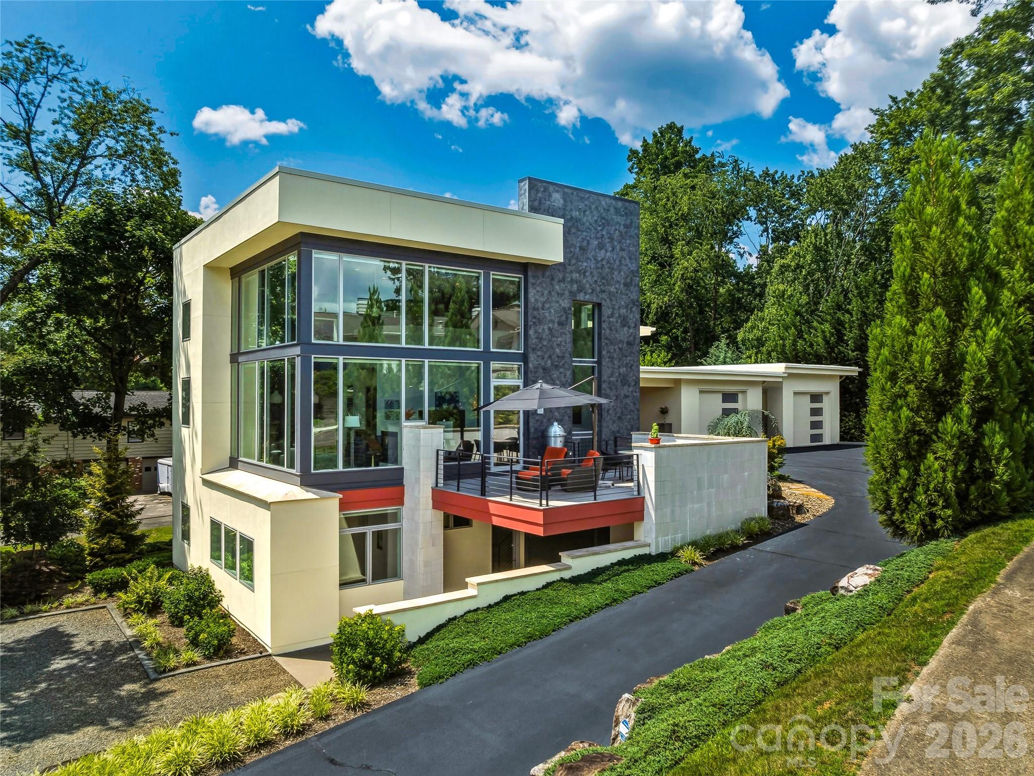 Commanding an extraordinary waterfront setting on Beaver Lake, this architecturally significant "Glass House" residence offers a rare blend of modern design, exceptional craftsmanship, and breathtaking natural beauty. Expansive walls of glass invite panoramic lake and mountain views into nearly every room, creating a home that feels both sophisticated and deeply connected to its surroundings.

The thoughtfully designed floor plan lives effortlessly on the main level, where a dramatic living space with soaring ceilings flows seamlessly into a chef's kitchen and an elegant primary suite complete with a spa-like bath and adjacent laundry. Designer lighting, custom finishes, and abundant natural light lend warmth and refinement throughout the home.

The lower level provides outstanding flexibility with spacious guest accommodations, a comfortable recreation room, dedicated office or studio space, and additional rooms easily suited for creative pursuits, fitness, or multigenerational living. A covered carport on this level offers convenient private access for family and guests alike.

Whether you're entertaining on a grand scale, displaying a curated art collection, or enjoying a serene morning overlooking the water, this exceptional property delivers a lifestyle defined by elegance, convenience and effortless luxury in one of North Asheville's most coveted locations.