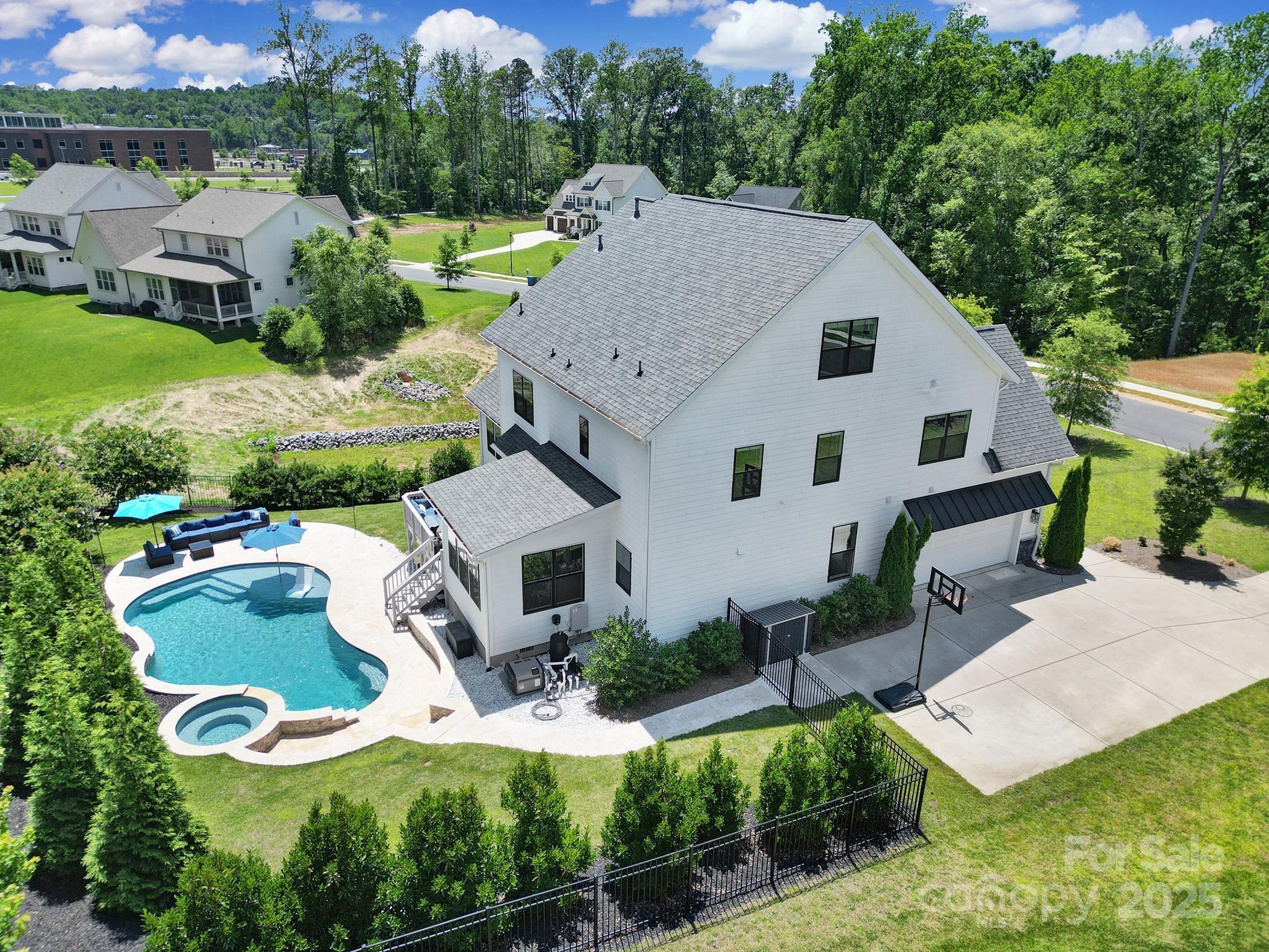 Welcome to the former Builder’s Model in desirable Nims Village! Situated on a beautifully landscaped corner lot, this 5-bedroom, 4.5-bath home offers an open floor plan with designer finishes and abundant natural light. The main level features a chef’s kitchen with quartz countertops, tile backsplash, stainless appliances, and a large island with bar seating. The spacious living area includes a cozy gas fireplace, while the main-floor primary suite boasts a spa-like bath with dual vanities, walk-in tiled shower, and generous closet. Upstairs offers additional bedrooms, full baths, a large bonus room, and a third-floor flex space perfect for media, fitness, or play. Step outside to your backyard oasis—complete with a heated saltwater pool and spa, perfect for relaxing or entertaining. Located in a sought-after Fort Mill community zoned for award-winning schools including Catawba Ridge High, and convenient to shopping, dining, and more!