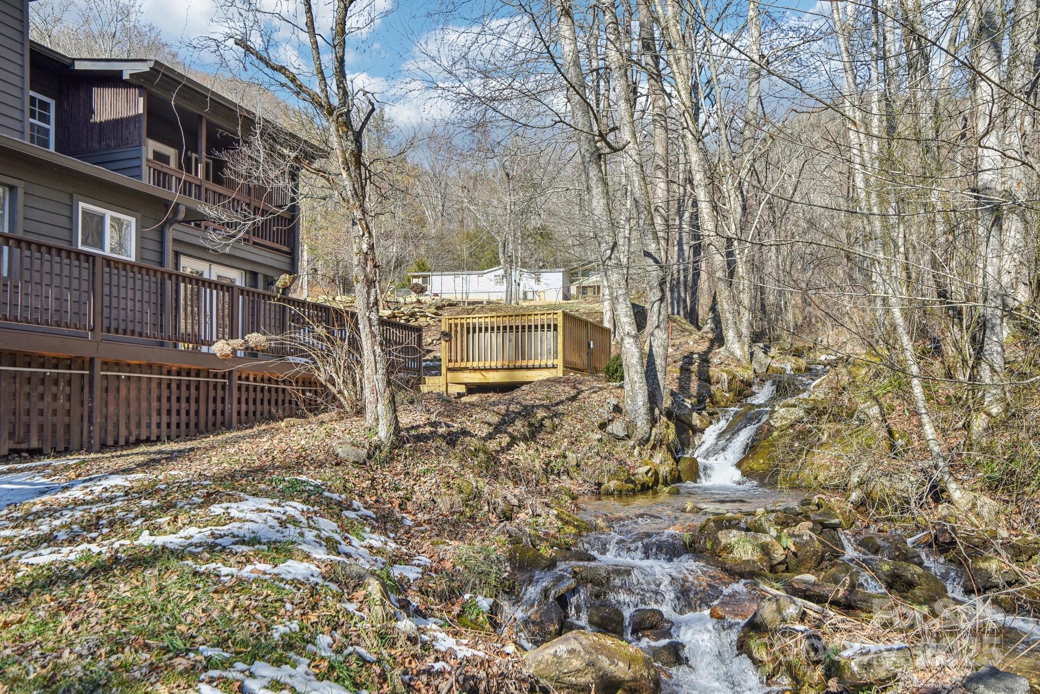 Creekfront, Views, and Unrestricted! This unique property is nestled along a roaring creek on 1/2-acre unrestricted lot with mountain views, this property offers a rare combination of serenity and adventure.  Inside, the home features 3 spacious bedrooms, ample living areas, and a layout full of character, perfect for customization to fit your needs. The finished basement, complete with a full kitchen, provides incredible versatility—ideal for a guest suite, rental potential, or additional living space. Multiple wood decks invite you to enjoy the beauty of the surrounding landscape, whether it’s sipping coffee by the creek or hosting friends for an outdoor gathering. Located less than half a mile from the entrance to Pinnacle Park, one of WNC's premier hiking destinations, this home is perfect for outdoor enthusiasts and nature lovers. This is mountain living at its finest, paired with the convenience of nearby Sylva. No storm damage and not in a flood zone.
