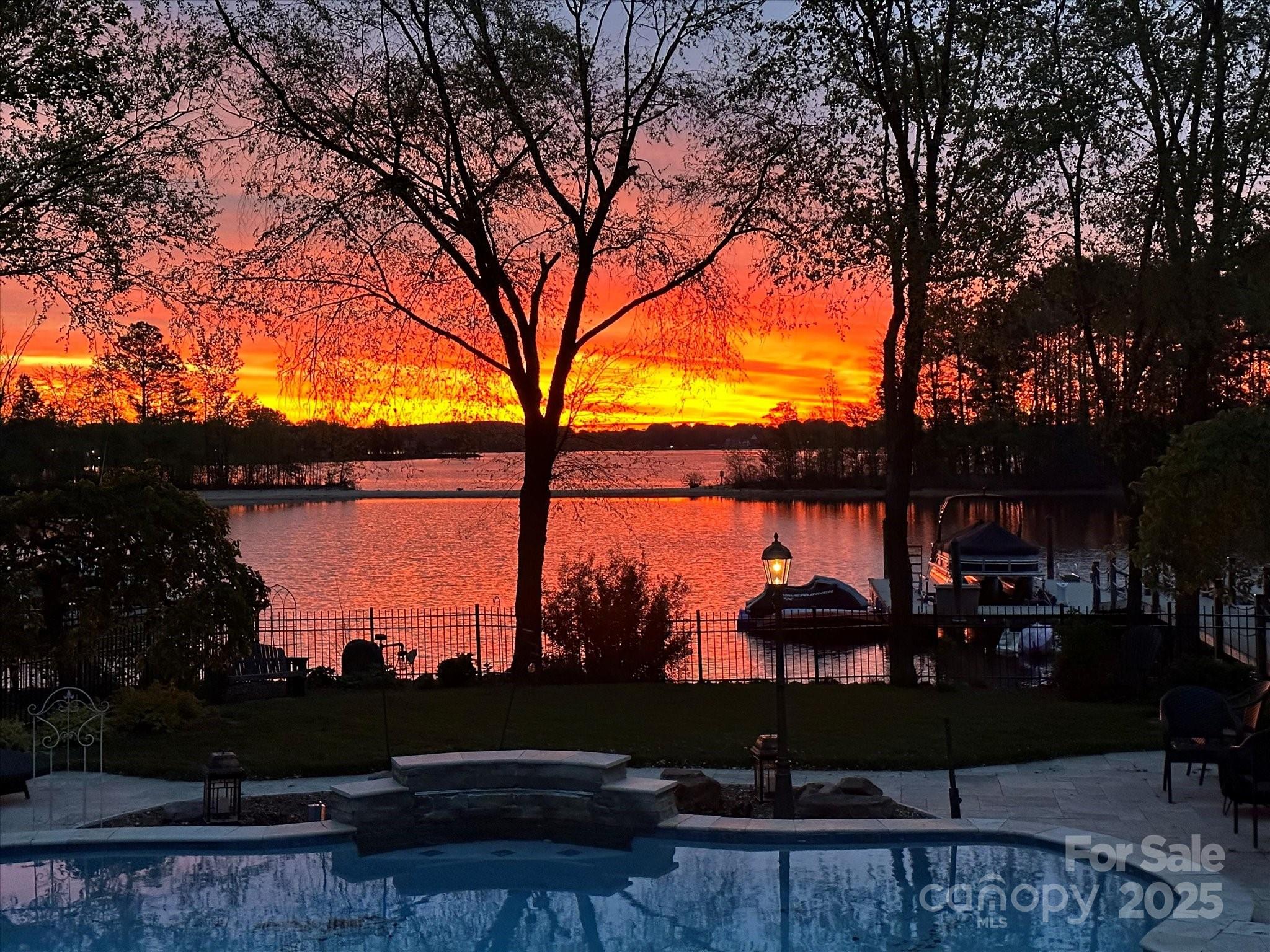 Resort-style living on Lake Norman with this spectacular sunrise waterfront home in The Peninsula under $3M!!!  Main level features radiant heated wide-plank tile floors, soaring ceilings, extensive millwork, formal dining, office with barn doors, and a spectacular chef’s kitchen with Sub-Zero, Wolf range, wine fridge, beverage drawers, and custom coffee center. Great room with fireplace opens to screened porch with fireplace and grilling deck, all overlooking heated saltwater pool, spa, and shared (deep water) dock with boat lift, jet ski ports, and kayak rack. Upstairs, the owner’s retreat boasts a sitting area with fireplace, spa bath, dual closets, and terrace with lake views. Secondary bedrooms include an ensuite with window seat, another with shared full bath and loft with custom built-in office/reading nook, plus a versatile bonus/4th bedroom with wet bar, walk-in closet, and window seat. 3-car garage, walk-up attic, and tremendous storage complete this exceptional home. Updated and Many Upgrades!