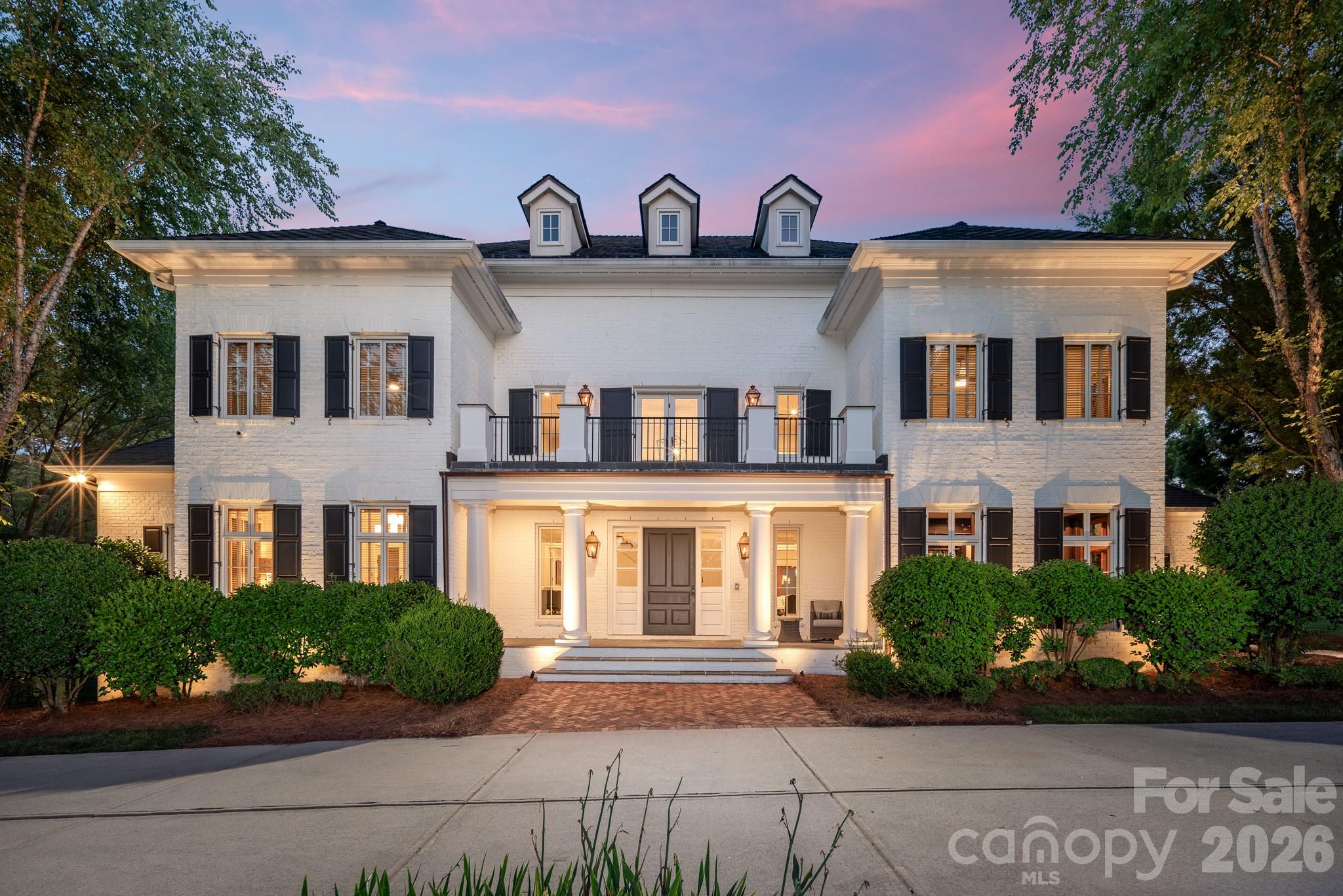 A rare Simonini-built estate on two private acres in Arbor Oaks, an exclusive gated enclave of just twenty homes. Completely reimagined with painted white brick, black shutters, and a Class 4 EcoStar synthetic slate roof carrying a 50-year warranty, this 10,000+ square foot, seven-bedroom residence delivers the most sought-after look in luxury today — with the craftsmanship to back it up. A dramatic two-story foyer with curved staircase opens to formal living spaces that flow into a warm keeping room with a second fireplace at the heart of the home. The showpiece Vanderloc kitchen features Calcutta marble, a Wolf dual-fuel range, full-size Sub-Zero, Miele built-in espresso machine, a coffee station with refrigerated drawers, commercial hood, and a lighted walk-in pantry — all backed by a full scullery and butler's pantry that keeps prep and cleanup out of sight. The main-level primary suite offers heated bathroom floors, a euro-style shower, and a fully built-out custom closet. The lower level lives like a private resort: theater, rec room with custom-lit dance floor, professional gym with Rogue equipment, a four-person Finnleo traditional/infrared sauna, dedicated cold plunge, teak floors, Sonos audio, and Philips Hue lighting. Outside, two levels of brick terrace surround a custom concrete saltwater pool with slide, spillover spa, and rain curtain beneath a restored pergola. Meticulously maintained with three new HVAC systems, Elan whole-home audio, Lutron lighting, and a full engineer's report remediated by the original builder. All of it 25 minutes to Uptown, 30 to CLT, and 10 to Concord-Padgett Regional — gated estate privacy in Charlotte's orbit, completely out of it the second you want.