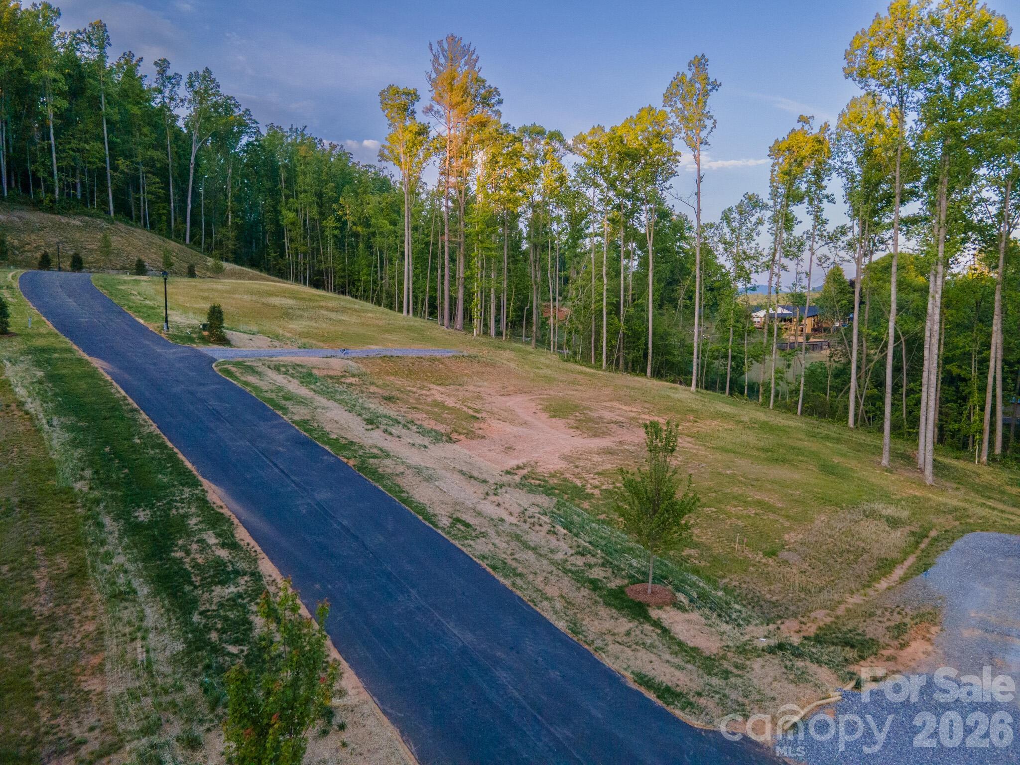 Homesite Five at Harris Cove is a generous parcel of about 0.87 acres with the long-range mountain views the community is known for. The driveway is already installed on engineered fill, easing the early lift of construction and removing one of the first big steps for the buyer. Set well back from the public road, the lot carries a calm that buyers tend to associate with much larger acreage. Southern exposure provides a strong base for passive-solar design, subject to the buyer's architect. A proposed home design by Tykke Homes is available for this homesite, with more information upon request; the design is intended to meet the community's architectural guidelines and reflects the quality and detail expected at Harris Cove.