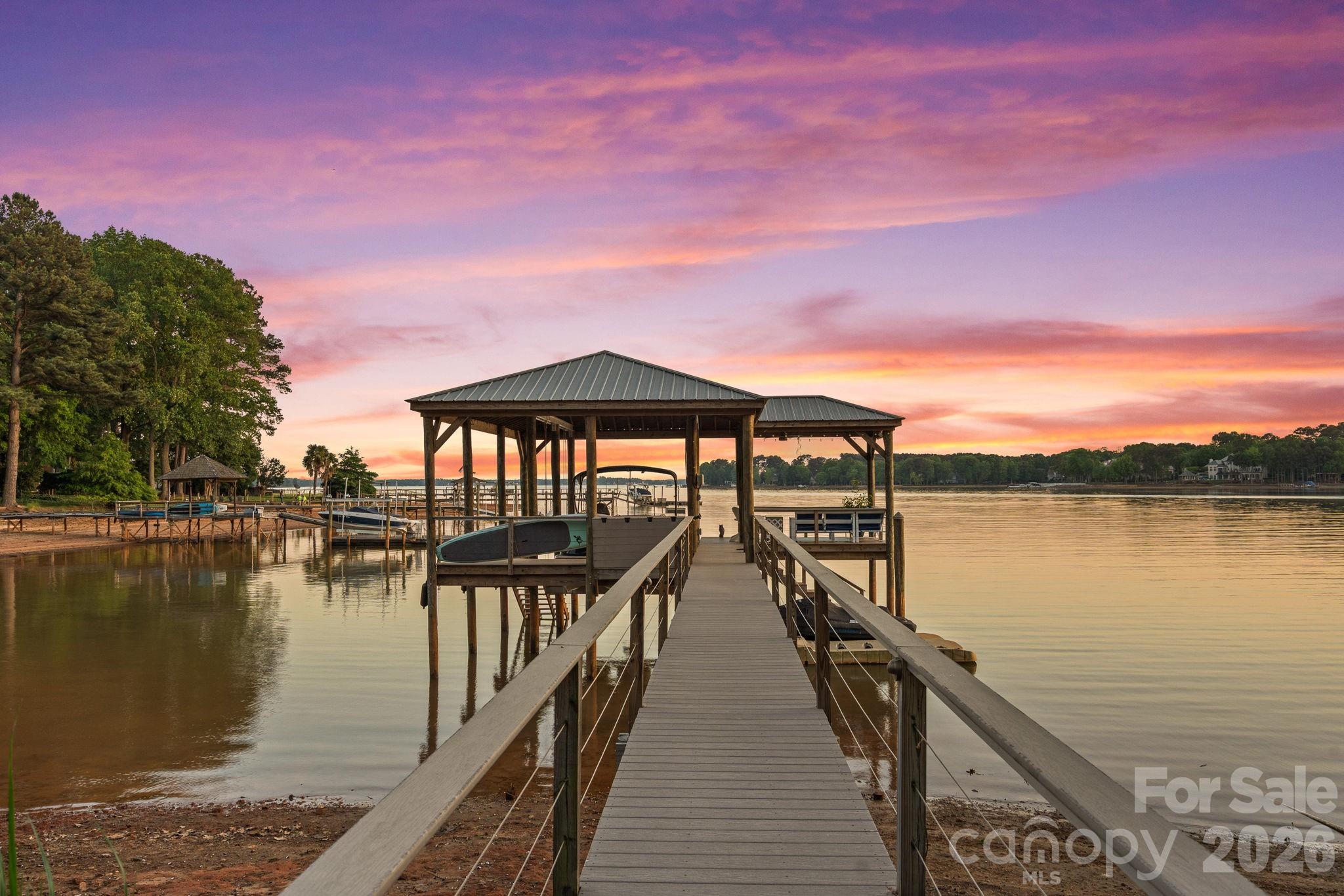 Tucked away on the highly coveted Isle of Pines Peninsula, just off the main channel of Lake Norman, 107 Beachview Drive offers a rare blend of privacy and a beautifully lake-inspired waterfront residence. Set on a oversized 1-acre lot with nearly 200 feet of shoreline, this beautifully renovated 4-bedroom home showcases over 4,100 square feet of thoughtfully designed living space with expansive lake views from nearly every room. Fully reimagined in 2019, the home features a stunning chef’s kitchen with custom cabinetry, quartz countertops, high-end appliances, pizza oven and a generous island that flows seamlessly into light-filled living and dining spaces designed to capture the water views & beyond. The main-level primary suite offers a true retreat with a spacious, spa-inspired bath and oversized walk-in closet, while additional bedrooms and flexible spaces provide ideal accommodations for guests, office, or recreation. Outdoor living flows naturally from the home to a covered pergola deck, screened porch, and landscaped yard that leads to the water’s edge, where a covered dock with seating and year-round deep water invite easy lake days and gorgeous sunset evenings. Don't miss the rare advantage of a "grandfathered" boat ramp and private beach; features hard to find on Lake Norman. Located near waterfront dining, 3 Golf Courses & TNGC Charlotte this no-HOA property combines convenience with a peaceful setting, offering the ultimate Lake Norman lifestyle in one of the area’s most desirable locations, all within top-rated school districts.