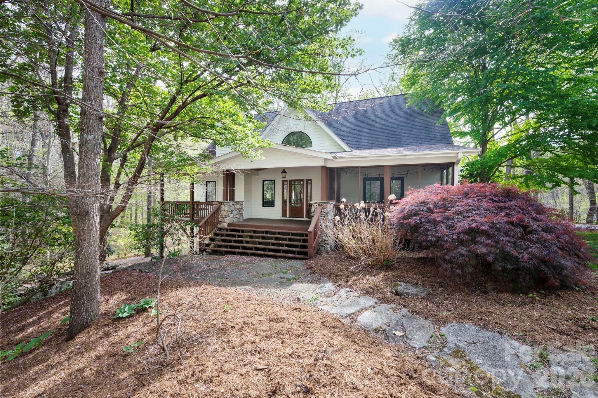 Set within the peaceful and picturesque Jones Cove Valley, this extraordinary property captures the quiet elegance of mountain living with a sense of privacy and grace that is increasingly rare. Surrounded by wooded beauty and enriched by a pond, waterfall, and layered outdoor spaces, the home feels timeless and deeply connected to its setting. Publicly offered for the first time, it is a singular opportunity to own a residence that has long been passed quietly from one steward to the next.
Inside, the home is a study in warmth, scale, and craftsmanship. Renovated in 2018, its interiors are defined by vaulted ceilings, exposed beams, rich hardwoods, and expansive windows that frame the surrounding landscape. A striking stone fireplace anchors the main living space, while the kitchen and dining areas blend understated sophistication with effortless function. The primary suite offers a true sense of retreat, while the upper and lower levels provide beautifully composed spaces for guests, work, wellness, and recreation. Separate living quarters above the detached garage add another layer of flexibility and privacy. With geothermal heating and cooling, high-performance systems, and a setting of exceptional tranquility, this is a home of uncommon beauty and enduring appeal.