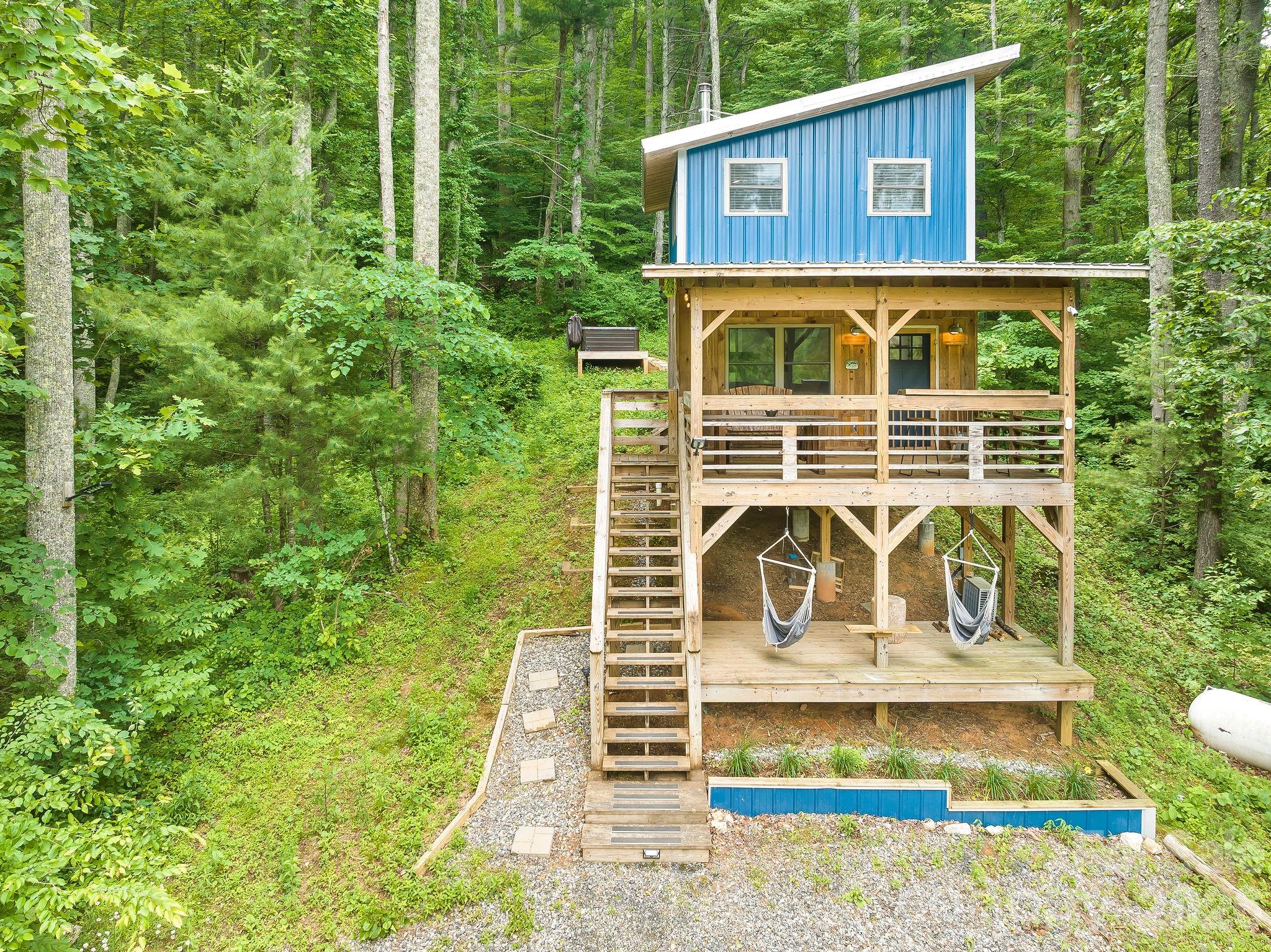 **Small Home – BIG Life!**

Welcome to the perfect mountain cabin retreat! Nestled in the woods of Marshall, NC, in the heart of the Blue Ridge Mountains, this charming site-built cabin offers privacy, tranquility, and more than 20 acres to explore. Sold fully furnished, this turnkey property features a proven rental history and excellent investment potential.

Conveniently located just 40 minutes from Asheville and 15 minutes from downtown Marshall, this cozy getaway blends rustic mountain charm with modern comfort. The loft-style sleeping area accommodates a queen bed and bunk beds, while the main level features a full kitchen and full bath with a tub.

Relax year-round beside the wood-burning fireplace or enjoy efficient heating and cooling with the new mini-split system installed in 2025, plus a propane backup heater. Step outside onto multiple decks to take in seasonal mountain views, then unwind in the brand-new hot tub surrounded by the peaceful sights and sounds of nature.

Adventure is never far away. Enjoy easy access to horseback riding, whitewater rafting, kayaking, ziplining, ropes courses, mountain biking, hiking, and the French Broad River, all within a short drive. Experience some of Western North Carolina's premier outdoor destinations while still enjoying complete privacy and seclusion.

Whether you're seeking a full-time residence, vacation getaway, or income-producing short-term rental, this private mountain retreat delivers the perfect blend of comfort, adventure, and mountain living.
