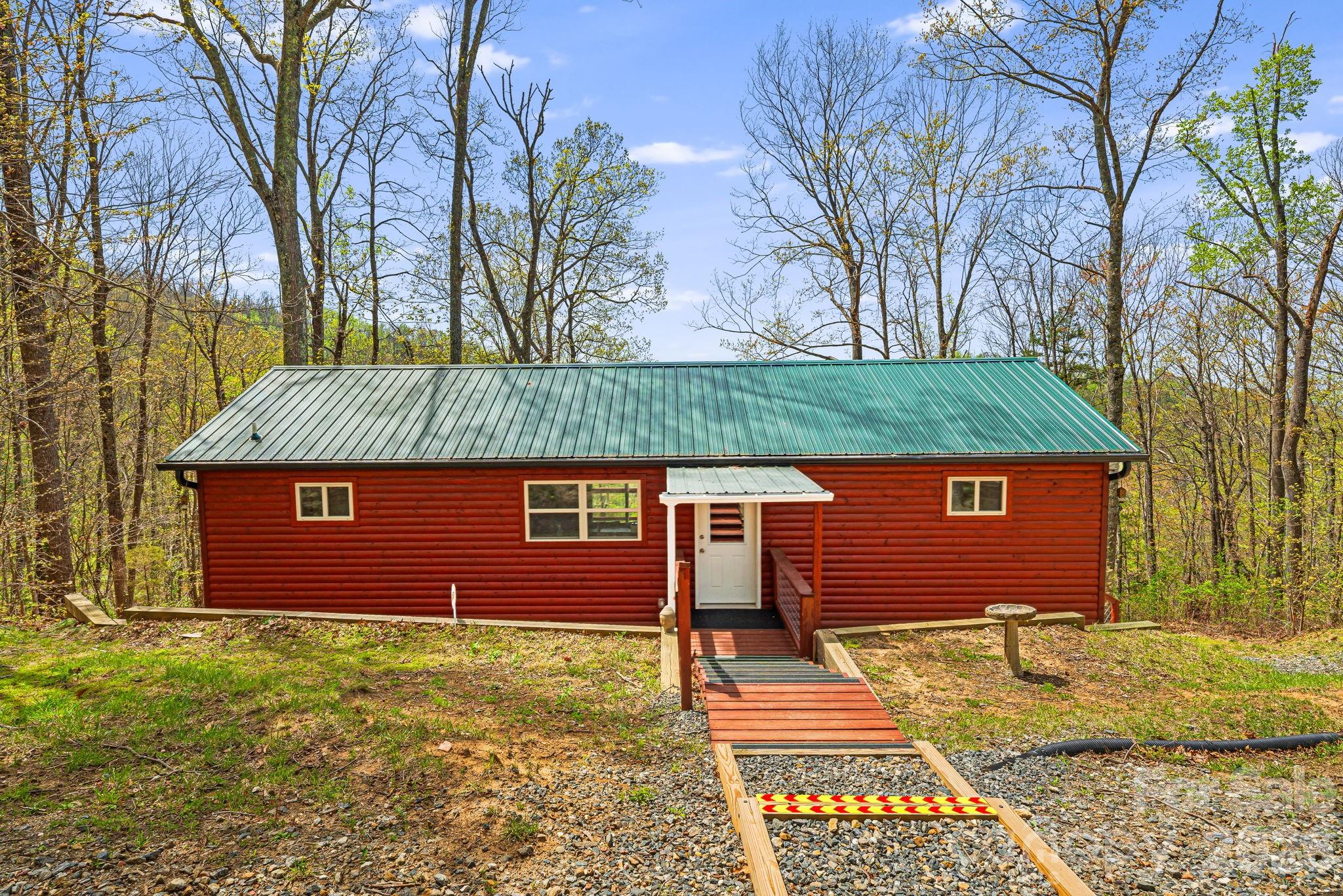 Meticulous craftsmanship shines in this like-new mountain cabin, tucked away on over 2 wooded acres with western-facing mountain views. Whether you're looking for a weekend escape or a full-time home, this peaceful spot offers the best of both worlds.  Inside, you'll find tongue-and-groove pine walls and vaulted ceilings. Large sliding doors let in lots of light and frame the mountain views, making the most of the quiet, private setting.  There are two bedrooms, each with their own full bath, plus a finished 480 sq ft daylight basement that's heated and cooled—perfect for a workshop, studio, or storage. The home is equipped with a tankless water heater, baseboard heat, and a combo washer/dryer.  Located just 10 min. from Weaverville and 20 minutes from downtown Asheville, you get convenience without sacrificing privacy.   Home has a shared well and a newly installed 1200 gallon water harvesting system with whole house filtration. Please no drive-bys.  The Jeep on the property is included with an acceptable offer.