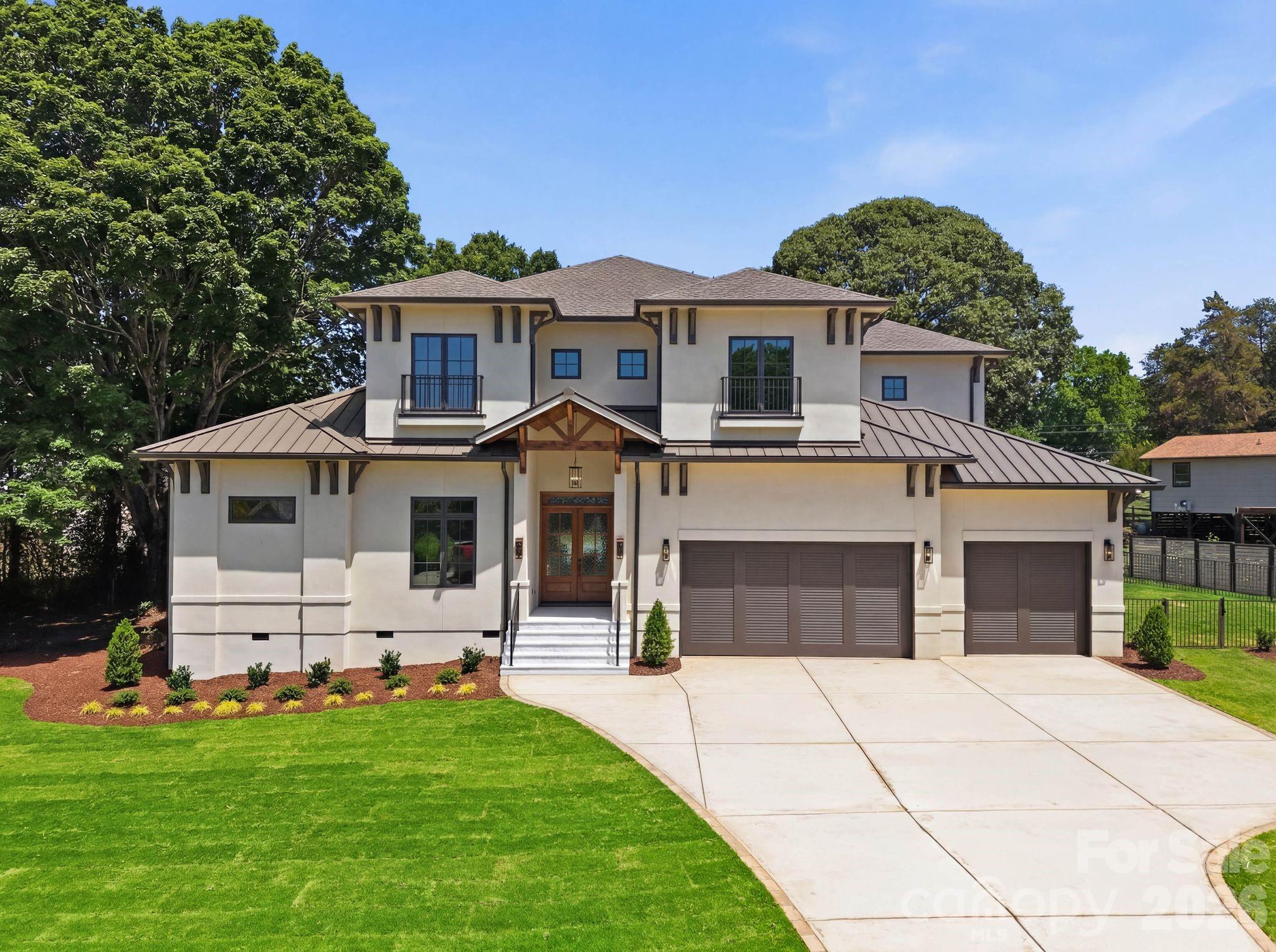 Modern sophistication meets timeless West Indies elegance in this extraordinary custom new-construction residence by Lagniappe Homes. Ideally positioned in the heart of Cornelius with lake access and directly across from Lake Norman, this 4,845 sq. ft. luxury retreat offers beautiful water views and a rare opportunity to own a thoughtfully designed new construction home in one of the area’s most coveted locations.

From the moment you arrive, the architectural presence is unforgettable. A full stucco exterior, aluminum-clad bronze windows, standing seam metal roofing accents, custom wood garage doors, and a stained mahogany entry door with beveled Flemish glass create a refined yet welcoming aesthetic. Stone entry steps, stained tongue-and-groove porch ceilings, and professionally designed landscaping further elevate the curb appeal.

Inside, soaring 12-foot ceilings, smooth-finish walls, engineered white oak flooring throughout, and custom wood ceiling details establish a warm modern elegance. The open-concept living spaces are designed for seamless indoor-outdoor entertaining, anchored by a dramatic 100-inch three-sided fireplace and expansive 14-foot Western multi-slide glass doors opening to the covered lanai.

The chef’s kitchen is both functional and stunning, featuring custom solid wood cabinetry, quartz countertops with full-height quartz backsplash, a 48” JennAir gas range, Venetian plaster hood, wine column refrigerator, under-cabinet lighting, and a fully equipped scullery complete with second dishwasher and refrigerator. Luxury conveniences continue throughout the home with dual laundry rooms, custom closet systems, pop-up charging outlets with wireless charging capability, glass cabinet lighting, floating shelf accent lighting, and a full wet bar upstairs.

The main-level primary suite offers a true spa experience with heated bathroom floors, oversized custom shower, soaking tub, dual walk-in closets, and enhanced sound-dampening insulation for privacy and comfort. Upstairs, three additional ensuite bedrooms accompany a spacious loft and second covered lanai.

Designed for modern living, the home includes a 400-amp electrical service, whole-home prewire for audio, video, ethernet, and security cameras, wired networking throughout, EV charging capability, Ring doorbell system, and low-voltage exterior and landscape lighting. Additional quality features include two tankless water heaters with recirculation system, dual 15-SEER HVAC systems, cast-iron plumbing downspouts for sound reduction, and well-fed irrigation.

Outdoor living rivals a private resort, highlighted by a custom heated pool and spa with waterfall and fire features, expansive covered lanai, outdoor storage room, and a custom putting green with LED-lit cups. The oversized garage features high ceilings designed to accommodate an automotive stacking lift.

Every detail of this exceptional residence has been carefully curated to deliver elevated design, superior craftsmanship, cutting-edge functionality, and effortless luxury living near the shores of Lake Norman.