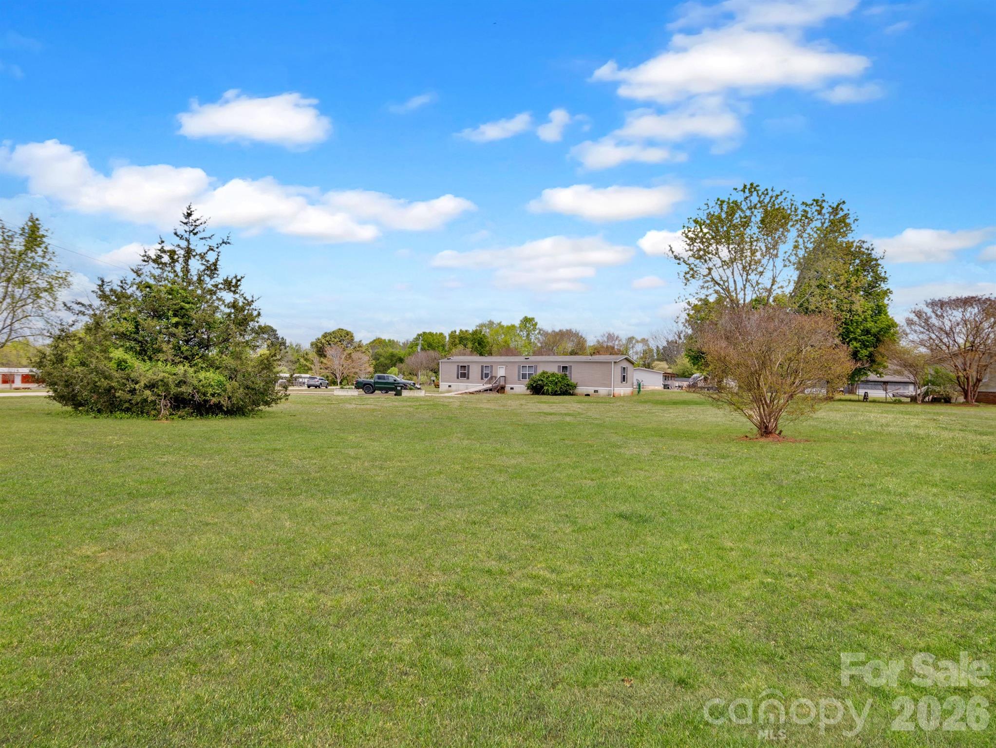 Situated on a spacious 1.27-acre corner lot, this home offers an open, level setting with plenty of room for entertaining.  Original home on the property was replaced with a new manufactured home in 2015. A wired, oversized detached garage provides the perfect space for a workshop or extra storage. Inside, the open floor plan connects the living room, dining area, and kitchen, creating a welcoming and functional layout. The kitchen features ample cabinetry and a large island with a breakfast bar, while the split-bedroom floor plan offers added privacy and comfort. Carpet replaced in 2 bedrooms.  Plenty of parking in the driveway. Enjoy the Quiet Country life! Seller is in the process of repairing the underpinning and the garage shed. The ramp entering the home will also be removed prior to closing.