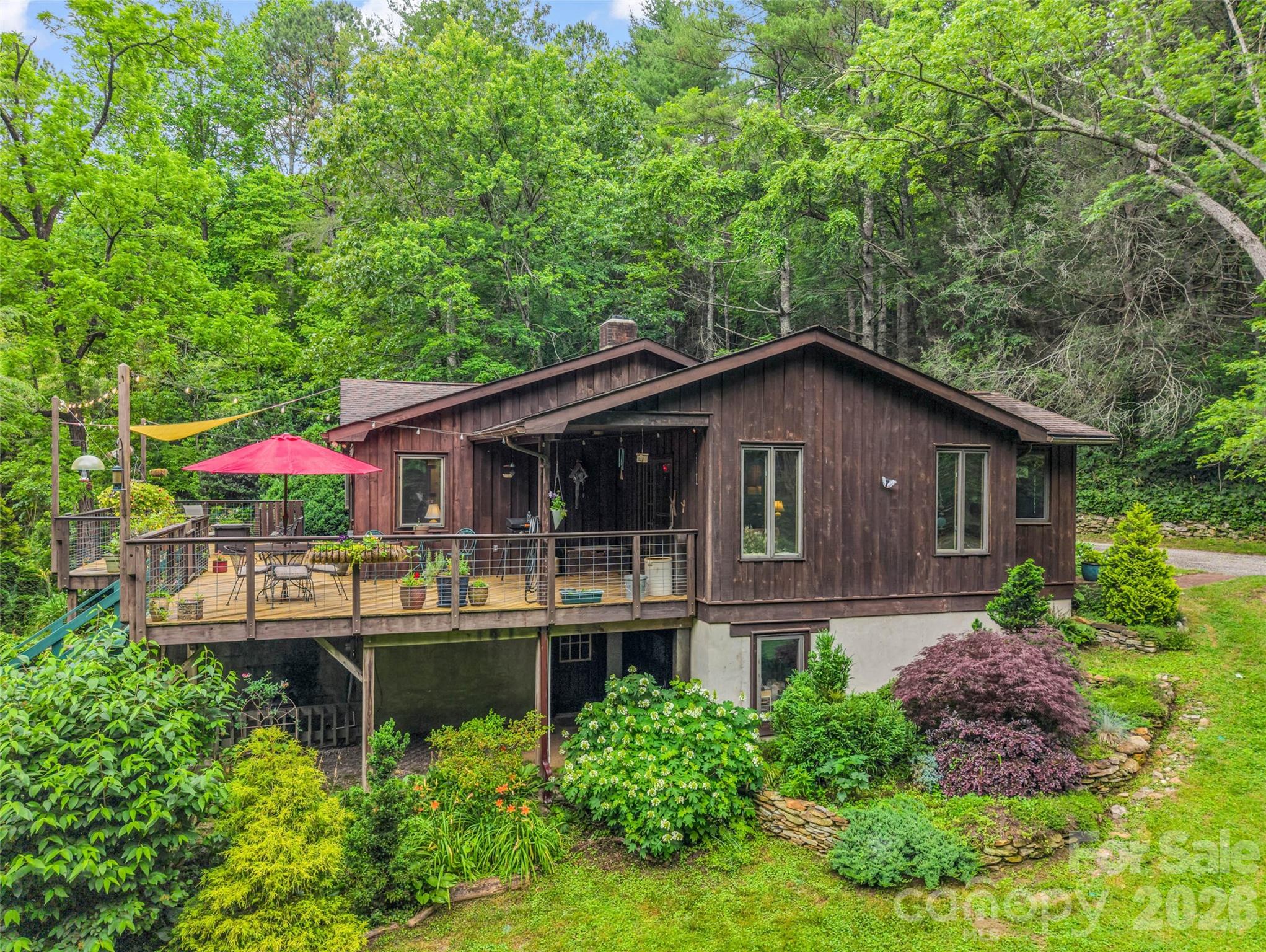 Welcome to Sunburst Hollow, a private 4.19-acre sanctuary where nature, privacy, and possibility converge in the heart of the Green River Valley. Surrounded by rolling land, open grassy spaces, and wooded privacy, this unique property offers an inviting setting for those seeking room to live, work, create, gather, or simply enjoy birds the beauty of the natural world. A rustic mountain home serves as the heart of the property, offering warm wood accents, inviting living spaces, and large windows that bring in natural light and views of the surrounding landscape. A spacious deck provides the perfect place to relax, entertain, or enjoy the sights and sounds of this peaceful setting. Beyond the home, the possibilities begin to unfold. A two-story building with water, electricity, and workshop space is well-suited for a variety of uses. Additional structures include a sleeping cottage with water and electricity, a storage barn, a goat barn, and a covered patio. Whether you envision a private homestead, creative retreat, hobby farm, wellness space, workshop, or simply a mountain escape, Sunburst Hollow offers the flexibility to make it your own. Conveniently located approximately 20 minutes from downtown Hendersonville and minutes from major highways, you'll enjoy the balance of privacy, natural beauty, and accessibility.