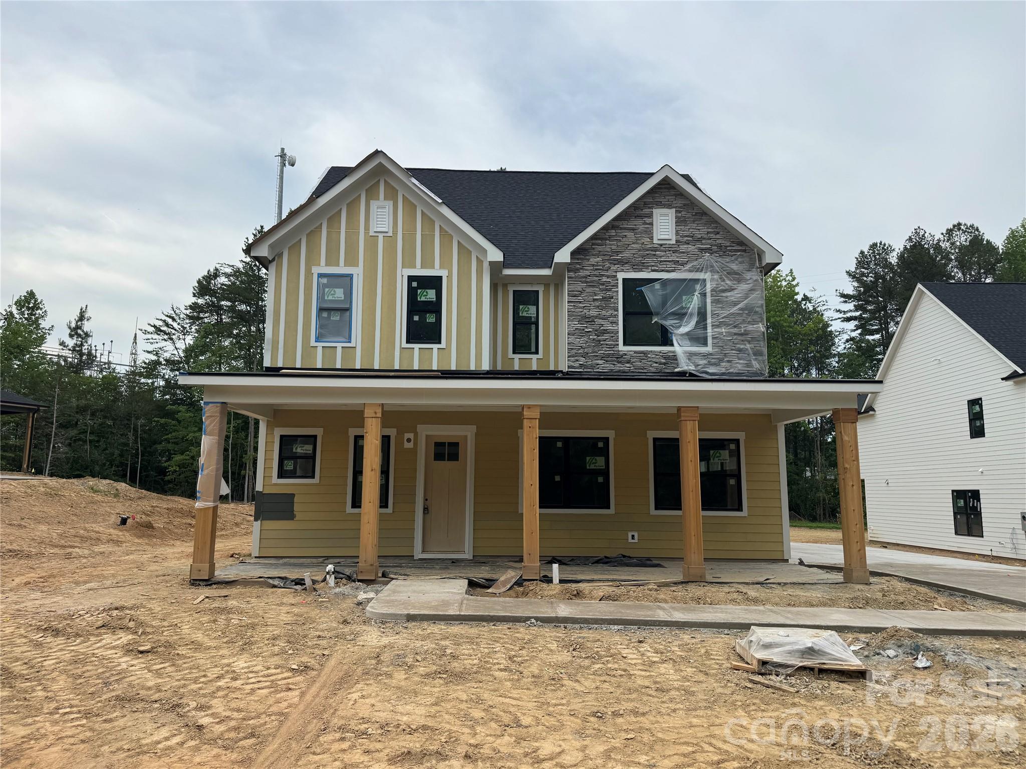 Welcome to 205 Parkdale Drive, a beautifully designed new construction home in Belmont offering 4 bedrooms, 3 full baths, and 2,986 square feet of thoughtfully crafted living space on a generous 0.56-acre homesite. Located approximately one mile from downtown Belmont, you’ll enjoy convenient access to local shops and dining. The exterior showcases James Hardie lap and board-and-batten siding in Pewter Green, accented by Centurion Grey ledgestone and rustic black architectural shingles for a timeless yet modern curb appeal. A covered front porch creates a warm and inviting entrance, while the rear covered porch provides the perfect space for outdoor entertaining or relaxing evenings at home. Inside, a light and airy palette sets the tone with Pure White walls, crisp trim, and cove crown moldings. Hand-scraped engineered hardwood floors flow throughout the main living areas, adding warmth and character. The two-story layout offers a functional and flexible design, including a main-level primary suite along with an additional bedroom and full bath ideal for guests or a home office. The kitchen serves as the heart of the home, featuring white shaker cabinetry, glass-front upper cabinets with LED lighting, quartz countertops including a striking Sahara Quartz island and Marengo Quartz perimeter surfaces, and a classic white subway tile backsplash. A KitchenAid appliance package and chrome Moen fixtures complete this beautifully appointed space. The family room centers around a ledgestone fireplace with a cedar mantle, and upgraded iron balusters enhance the architectural detail of the staircase. The primary suite offers a spa-inspired retreat with quartz countertops, white shaker cabinetry, framed mirrors, chrome fixtures, and a tiled shower finished in matte porcelain with basketweave accents. With a two-car attached garage, quality finishes throughout, and a prime location just minutes from the heart of Belmont, this home perfectly blends style, comfort, and convenience.