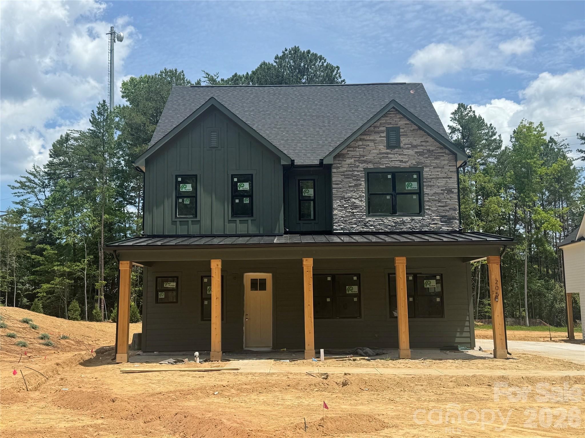 Welcome to 205 Parkdale Drive, a beautifully designed new construction home in Belmont offering 4 bedrooms, 3 full baths, and 2,986 square feet of thoughtfully crafted living space on a generous 0.56-acre homesite. Located approximately one mile from downtown Belmont, you’ll enjoy convenient access to local shops and dining. The exterior showcases James Hardie lap and board-and-batten siding in Pewter Green, accented by Centurion Grey ledgestone and rustic black architectural shingles for a timeless yet modern curb appeal. A covered front porch creates a warm and inviting entrance, while the rear covered porch provides the perfect space for outdoor entertaining or relaxing evenings at home. Inside, a light and airy palette sets the tone with Pure White walls, crisp trim, and cove crown moldings. Hand-scraped engineered hardwood floors flow throughout the main living areas, adding warmth and character. The two-story layout offers a functional and flexible design, including a main-level primary suite along with an additional bedroom and full bath ideal for guests or a home office. The kitchen serves as the heart of the home, featuring white shaker cabinetry, glass-front upper cabinets with LED lighting, quartz countertops including a striking Sahara Quartz island and Marengo Quartz perimeter surfaces, and a classic white subway tile backsplash. A KitchenAid appliance package and chrome Moen fixtures complete this beautifully appointed space. The family room centers around a ledgestone fireplace with a cedar mantle, and upgraded iron balusters enhance the architectural detail of the staircase. The primary suite offers a spa-inspired retreat with quartz countertops, white shaker cabinetry, framed mirrors, chrome fixtures, and a tiled shower finished in matte porcelain with basketweave accents. With a two-car attached garage, quality finishes throughout, and a prime location just minutes from the heart of Belmont, this home perfectly blends style, comfort, and convenience.