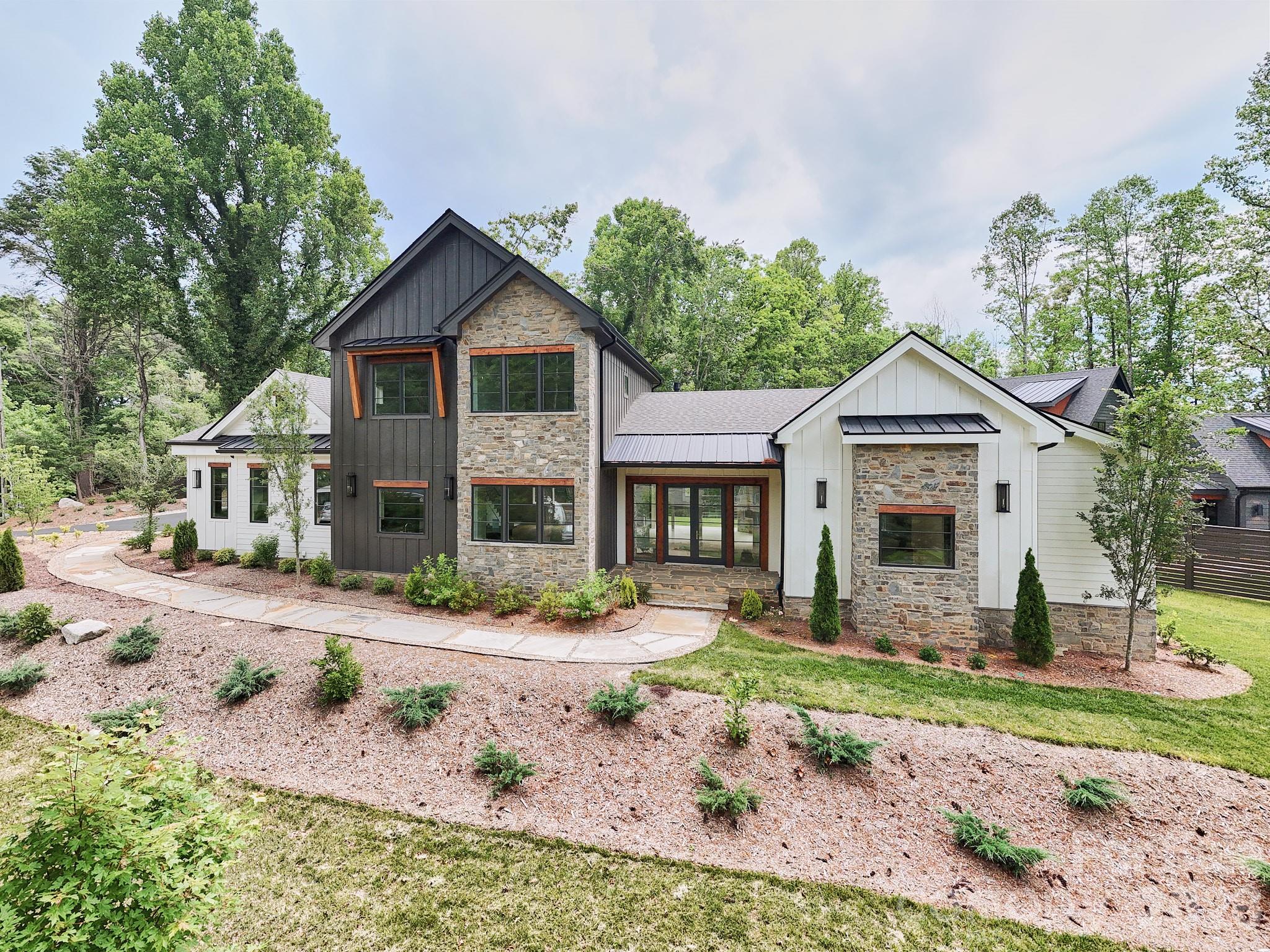 Less than one mile from the heart of downtown Brevard, this newly completed luxurious modern mountain residence offers a rare combination of walkable luxury, refined architectural design, low-maintenance new construction, and exceptional long-term quality. Set on a level 0.61-acre homesite with city water, city sewer, natural gas, winter mountain views, no HOA, and in-ground irrigation, the home delivers the ease of in-town living with the privacy, comfort, and craftsmanship of a custom mountain residence. Designed for both everyday living and effortless entertaining, the main living area features soaring ceilings, exposed beams, wide-plank wood floors, abundant natural light, and a dramatic stone fireplace that anchors the room. The open layout flows beautifully into the amazing chef’s kitchen, complete with premium custom cabinetry, elegant countertops, large center island, gas cooktop, wall oven, walk-in pantry, and high-end GE Monogram appliances. The main-level primary suite offers a peaceful retreat with a spa-inspired bath, soaking tub, generous walk-in shower, and spacious walk-in closet. Additional bedrooms and flexible living areas provide comfortable space for guests, family, office, media, or hobbies. Outdoor living is one of the home’s defining features. A covered rear terrace with its own fireplace creates a year-round setting for morning coffee, evening gatherings, quiet weekends, or entertaining after a day spent enjoying everything Brevard has to offer. The location is one of the home’s strongest lifestyle advantages. Less than one mile from downtown Brevard, owners can enjoy restaurants, coffee shops, galleries, boutiques, live music, festivals, and the welcoming energy of Main Street within minutes of home. Outdoor recreation is equally close, with Pisgah National Forest, DuPont State Forest, waterfalls, hiking, mountain biking, fly fishing, and scenic mountain drives all part of the surrounding lifestyle. Behind the home’s polished design is an uncommon construction story. Built with rare structural steel framing, the residence offers exceptional strength, stability, and long-term durability compared with conventional wood framing. Steel construction resists warping, settling, moisture, pests, and fire, creating a quieter, stronger, and more enduring home designed for generations of ownership. Ideal as a full-time residence, luxury second home, or refined mountain retreat, this property offers one of Brevard’s most compelling combinations: new custom construction, elevated custom finishes, outdoor living, advanced structural quality, and exceptional proximity to both Main Street and the outdoor lifestyle that makes Brevard one of Western North Carolina’s most treasured mountain towns.