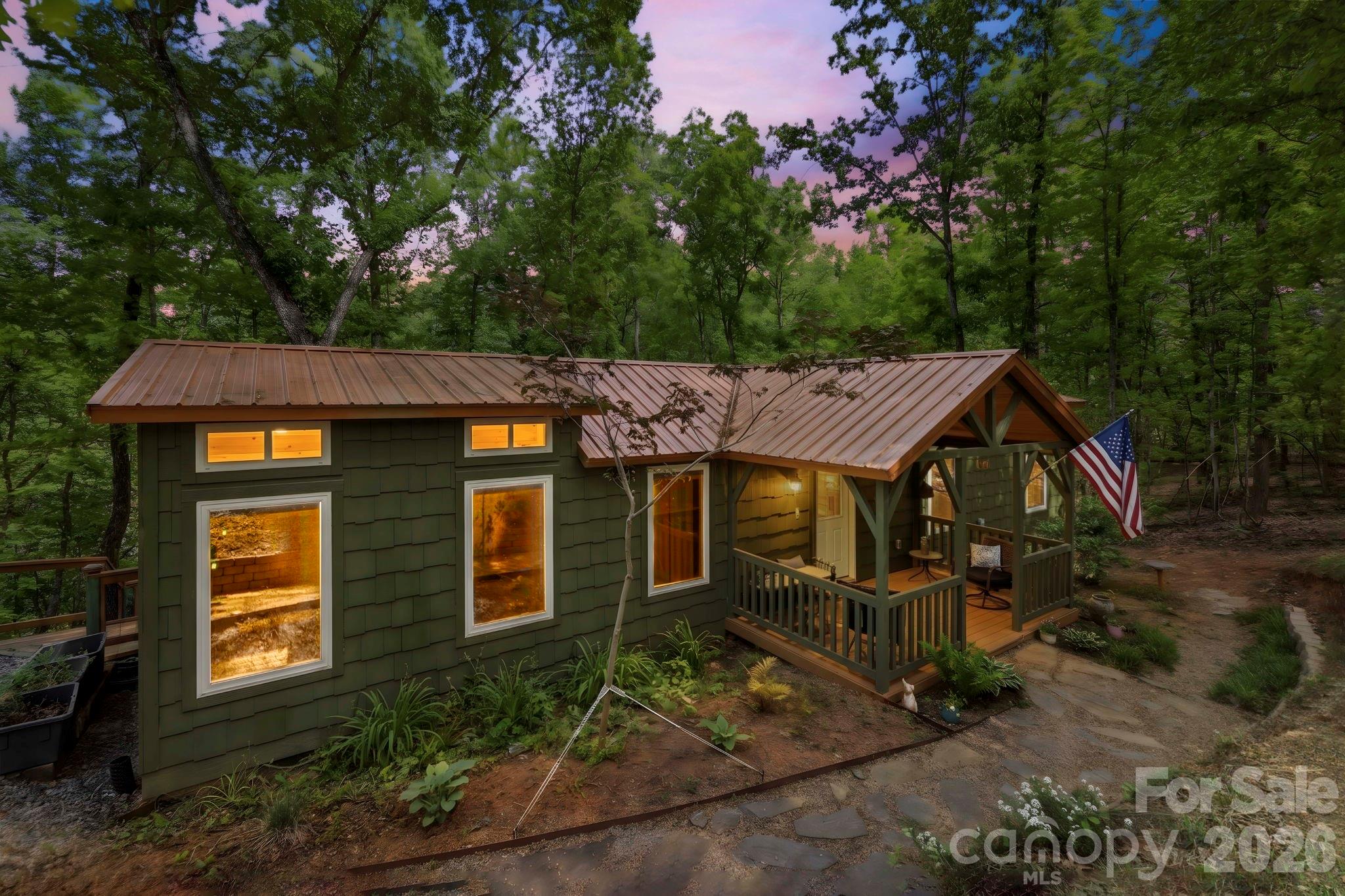 THIS CHARMING COTTAGE IS LISTED $25K BELOW RECENT APPRAISAL!!  This home lives much larger than the sqft.  With screened in outdoor room, front porch and back deck, it feels so much bigger.  It is designed for comfort and efficiency close to groceries, restaurants, Lake Lure and the Tryon Equestrian Center. The property features 2BR and a loft area creating an ideal retreat or investment opportunity. The level knoll adjacent to the garage presents excellent opportunity for constructing a primary residence, or add tiny homes for max income. Vehicle accommodation is generous, featuring 2-car detached garage, 1-car carport and ample parking.The outdoor living spaces are testament to relaxed country living. Welcoming covered front porch invites morning coffee moments, while screened-in back porch offers bug-free enjoyment of nature's symphony. The sunny back patio area, complete with a fire pit table, provides the perfect setting for evening gatherings under the stars. This move-in ready home comes completely furnished, allowing you to start living your dream lifestyle immediately. Find your investment property now before the crowds return as Lake Lure is opening up!  Recently inspected well, new well pressure tank w/iron and ph filter.  When you pull in and out of the drive, it feels like you are living in your own lush green world.  Come see!!