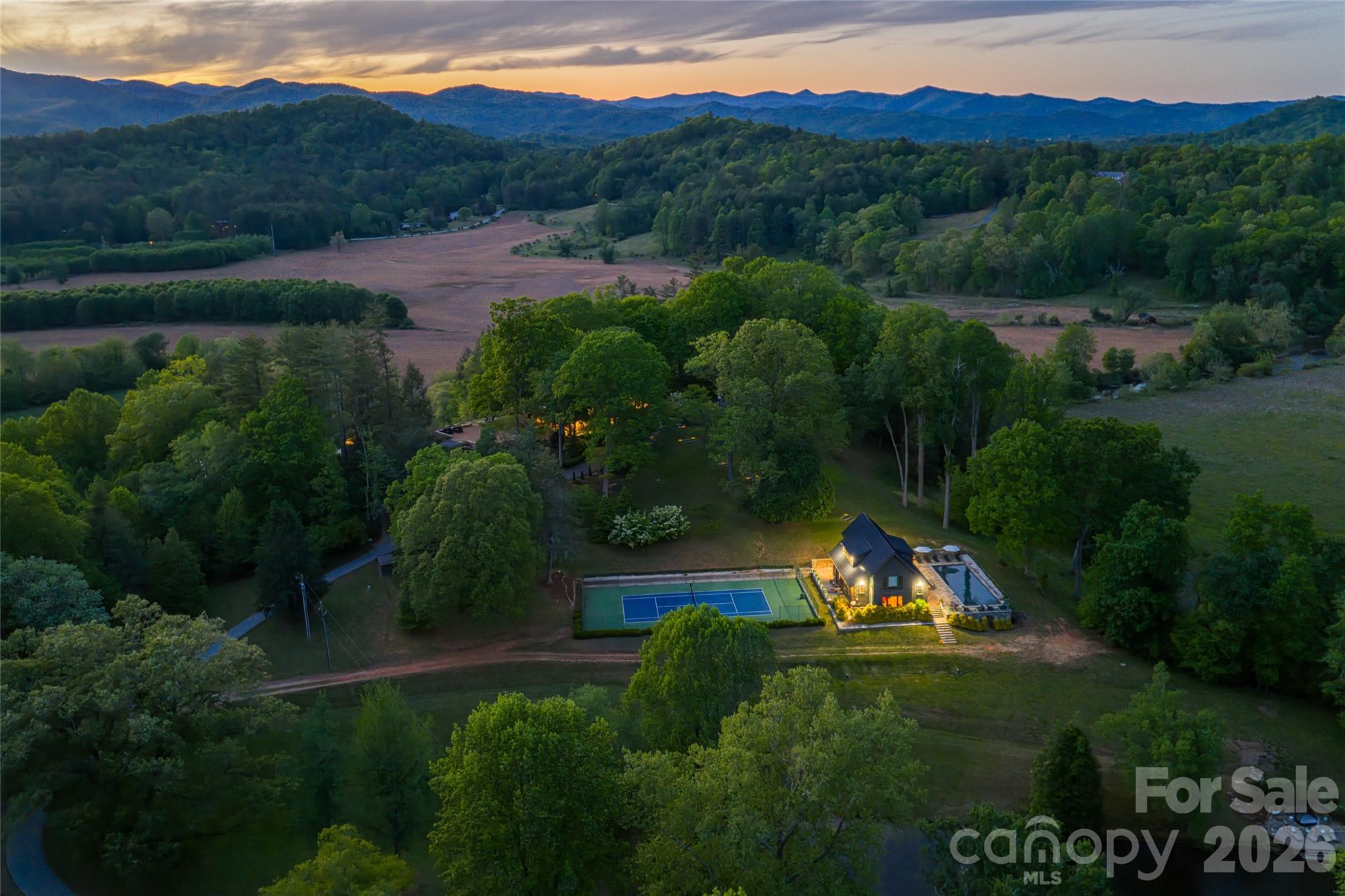 Blue Fish Farm is one of the most significant legacy offerings in the Blue Ridge Mountains, an extraordinary 160-plus-acre riverfront estate in Brevard, where privacy, scale and natural beauty converge along more than a mile of the French Broad River. Just minutes from Pisgah National Forest, DuPont State Forest and the region’s iconic waterfalls, this is a rare opportunity to own an irreplaceable Western North Carolina retreat. Originally designed by Platt Architects, the estate reflects a timeless mountain-modern aesthetic, blending refined craftsmanship with materials that echo the surrounding landscape. Across more than 12,700 square feet of combined living space, the property unfolds as a curated collection of residences, including a primary home, two guest cottages and a pool house, each thoughtfully positioned to capture river, pasture and mountain views. The main residence is warm, sophisticated and deeply connected to its setting, featuring heart pine flooring, natural bluestone, custom millwork and expansive windows that frame the landscape in every direction. Open-concept living spaces transition seamlessly to covered porches and outdoor entertaining areas, creating an effortless indoor-outdoor lifestyle synonymous with luxury mountain living. A series of guest residences provides exceptional flexibility for multi-generational living, private retreats or luxury rental potential. The Treehouse offers an intimate escape tucked into mature forest canopy, while The Hideaway delivers generous scale and privacy. The Pool House elevates the experience further with a full kitchen, fitness area, home theater, and direct access to a heated pool and tennis court, designed for relaxation and recreation. The land itself is the defining feature, over 160 acres of rolling pasture, hardwood forest, and curated grounds with three spring-fed ponds, an established trail system and expansive river frontage ideal for fly fishing, kayaking, and exploration. Whether envisioned as a private family compound, equestrian estate, working farm or corporate retreat, the possibilities are as expansive as the property itself. Despite its remarkable seclusion, Blue Fish Farm is less than 10 minutes from downtown Brevard’s vibrant dining, breweries and boutique shopping, and within easy reach of Hendersonville, Asheville Regional Airport and Asheville’s renowned cultural scene. Lake Toxaway and its private club amenities are also nearby, offering an added layer of lifestyle appeal. Blue Fish Farm is more than a property, it is a generational estate, a French Broad River sanctuary and a rare convergence of luxury, land and legacy in one of North Carolina’s sought-after mountain destinations.