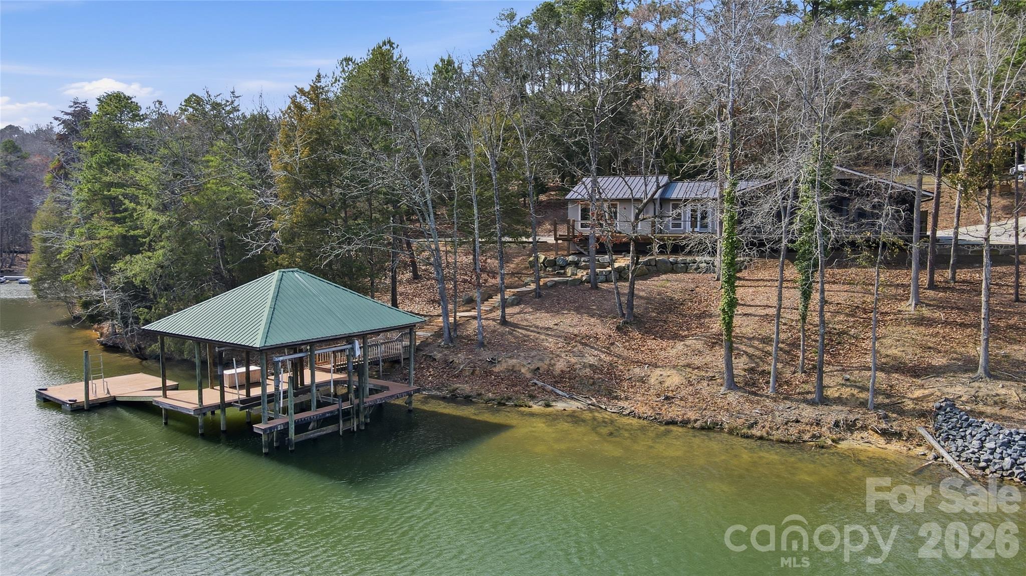 Looking for tranquility & privacy? Find it in this charming one-level waterfront home with breathtaking lake views. Perfectly designed for lake living and outdoor enjoyment, this beautiful 2.15-acre property features a gated entry and approximately 490 feet of shoreline along a protected cove that opens to the sought-after Big Allison section of Lake Wylie. Outdoor living takes center stage with a fabulous 400 sq. ft. screened porch with wood burning stone fireplace, spacious deck with metal railings, stone patio, and a covered dock complete with boat lift and swim platform. Inside, you'll find this amazing, updated home is loaded with character and offers a bright and open floor plan, beautiful flooring, warm wood ceilings, and stunning lake views from nearly every room. The lake-facing great room features expansive water views and a striking stone fireplace, creating a warm and inviting gathering space. The updated kitchen will delight any home chef, featuring stainless steel appliances, granite countertops, and a large center island, all flowing seamlessly into the dining area with a convenient wet bar for easy entertaining. This thoughtfully designed home offers three spacious bedrooms and 3 full baths, providing comfort and privacy for family and guests alike. Additional features include a metal roof, large storage building, no HOA, and a prime location just minutes from shopping and dining. Enjoy the best of waterfront living with privacy, spectacular views, room to expand, SC taxes, and sought after Clover schools!