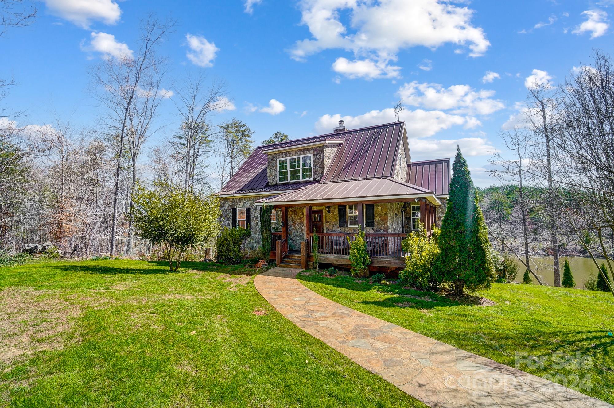 Nestled on 28 acres & a 5 acre pond, this charming stone cottage offers the epitome of peaceful countryside living. Features incl: wrap-around front porch;  Main Level incl: Updated kitchen w/new appliances, granite counters, & plenty of cabinetry; Living/Dining area w/stone fireplace offers flexibility (see staged photos); Primary BR w/ensuite bathroom has updated shower. The 45ft. screened porch overlooking the pond is accessible from the LR & primary BR. Upstairs: 2 more BR’s w/2 full baths, along with flex space for playroom or office:  The walk-out basement has 2 more BR’s, 1 bath & a flex space (think gym or adding a sauna). The utility rm incl. a water filtration system.  This daylight bsmt. has access to the lower 45’ patio with more opportunity to enjoy the pond. A portion of the land has been cleared & is ready for building a large garage/workshop.  Don't miss your chance to own this stunning stone cottage in Clover, SC and don’t forget that Clover Schools are highly rated!