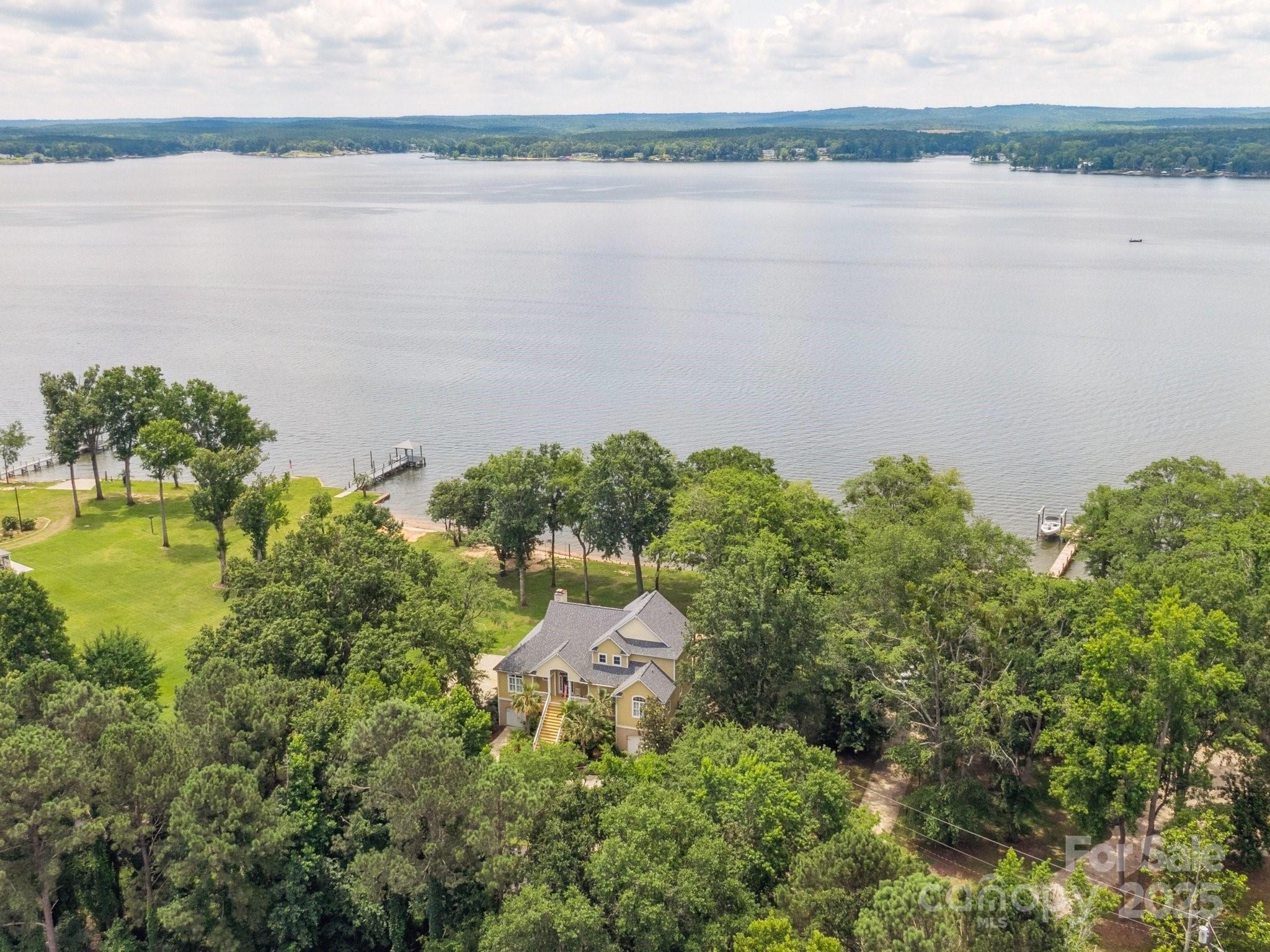 Breathtaking Custom Lakefront Estate on Main Channel! Every room boasts panoramic water views in this beautifully crafted home with rich hardwoods and quality millwork throughout the main level. With 4 bedrooms and 5 full baths, enjoy 2 bedrooms on main including a spacious owner’s suite with private balcony, plus an ensuite and another balcony-access bedroom upper level, plus loft—ALL with brand-new carpet. A gourmet kitchen offers counter seating and opens to a vaulted great room with fireplace and built-ins. Entertain with ease on the expansive covered porches, screened porch, and multiple decks. Outdoor luxuries include a hot tub, patio with fire pit, beach area, private boat ramp, boat lift, and two jet ski ports. The lower level features a rec room, flex room, full bath, and kitchenette—with elevator access to the main level. Ample storage, workshop, 2-car garage, washer/dryer, and new refrigerator convey. Lake living at it's finest on a rare Lake Wateree, light-filled retreat. Credit of $2500 at closing with preferred lender.