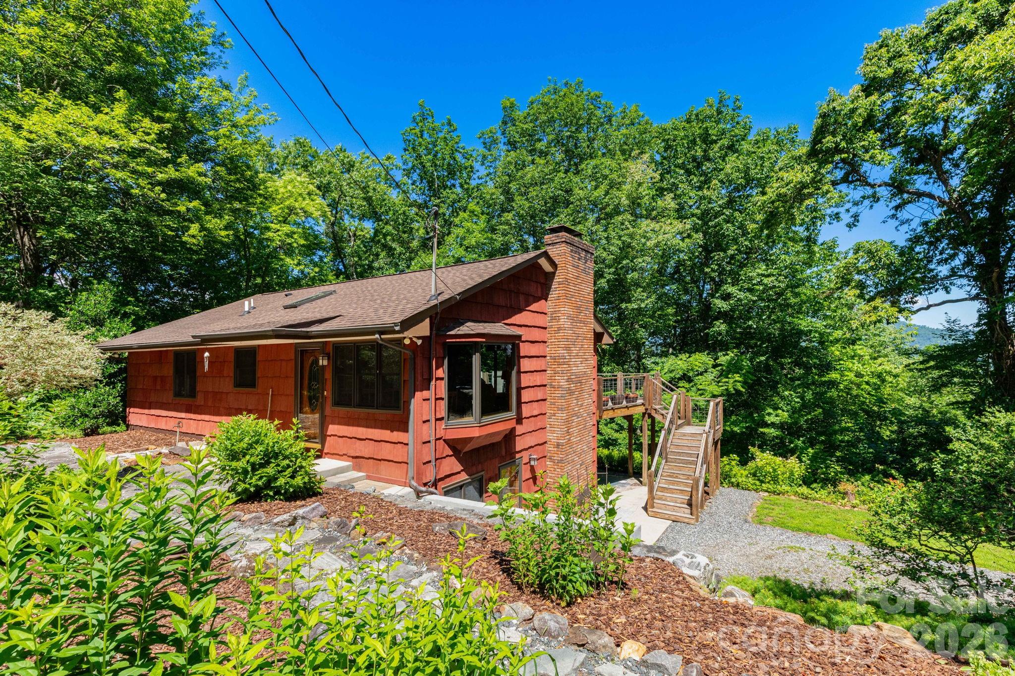 You must see this one in person to experience the real allure of this mountain oasis! Discover the perfect blend of mountain charm, privacy, and convenience at 168 Blossom Ridge. This beautifully maintained 3-bedroom, 2-bath home welcomes you with vaulted ceilings, rich wood accents, and gorgeous hardwood floors throughout. The open-concept living area features a bay window dining space and a wall of sliding glass doors that capture winter mountain views, with the potential for year-round vistas through selective tree pruning. The inviting living room centers around a wood-burning fireplace, while the kitchen offers stainless steel appliances, a large breakfast bar, and oversized pantry. The main level includes a spacious bedroom with a walk-in closet and full hall bath. The finished lower level features a large family room with a woodstove, two additional bedrooms, a full bath, additional exterior entrance, and a custom laundry room with built-in cabinetry and workspace. Step outside to enjoy the expansive deck with views, covered patio, shaded backyard with firepit, and exceptional terraced landscaping. Garden beds, mature blueberry bushes, asparagus, mint, and more create a true outdoor retreat. A detached garage provides excellent workshop or storage space. Enjoy high-speed internet, short-term rental potential, and a welcoming community. Surrounded by nature yet conveniently located just 10 minutes from shopping and restaurants on New Leicester Highway and only 20 minutes from downtown Asheville, this property offers the best of both worlds. Schedule your showing today and experience everything 168 Blossom Ridge has to offer.