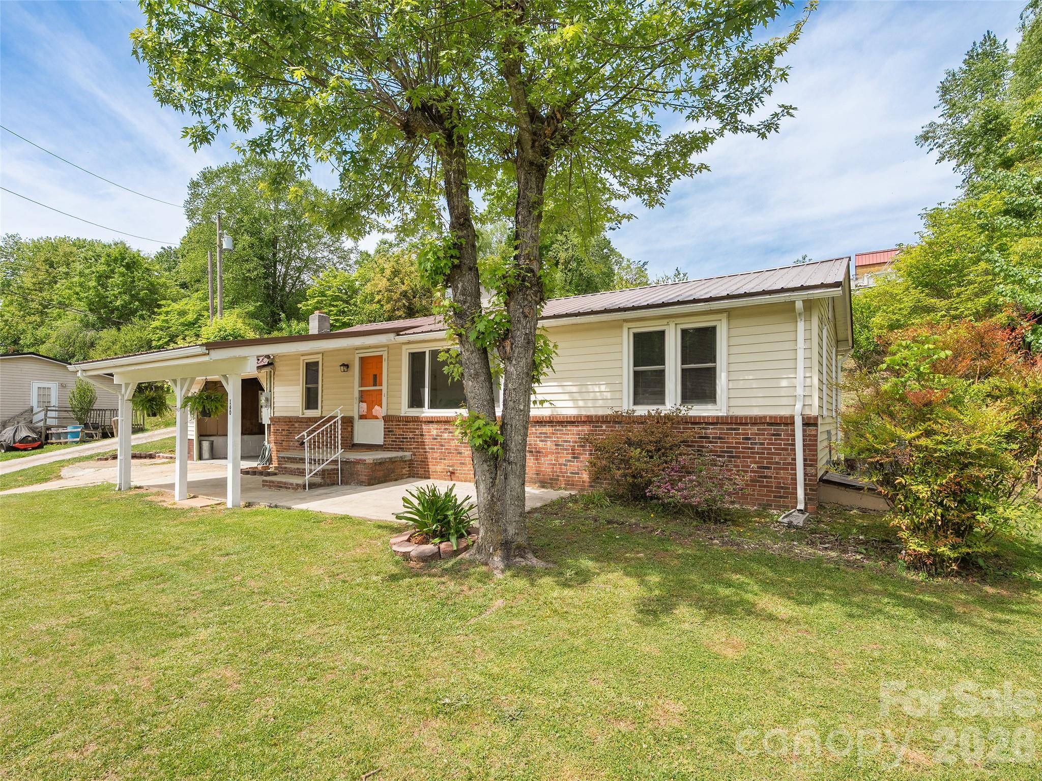 This charming one owner 3-bedroom, 1-bath brick home with vinyl siding sits on a spacious corner lot in a wonderful, stable neighborhood. Perfectly located in town with easy access to I-40 and 23/74, it offers convenience without sacrificing peaceful suburban living. Step inside to a bright formal living room and separate formal dining room. The home features updated plumbing and electrical throughout, a new HVAC system for year-round comfort, and a fresh metal roof that ensures low maintenance and peace of mind. Energy-efficient vinyl windows help keep utility bills in check. The functional layout includes a convenient laundry/mudroom, perfect for busy households. Outside, enjoy two covered patios—one in front and one in the rear—great for relaxing, grilling, or watching the kids play in the yard. Additional highlights include city water and sewer, Spectrum cable availability, and a single-car carport for protected parking. This well-maintained home combines classic appeal with modern updates, making it move-in ready for first-time buyers, downsizers, or investors. Don’t miss this fantastic opportunity.