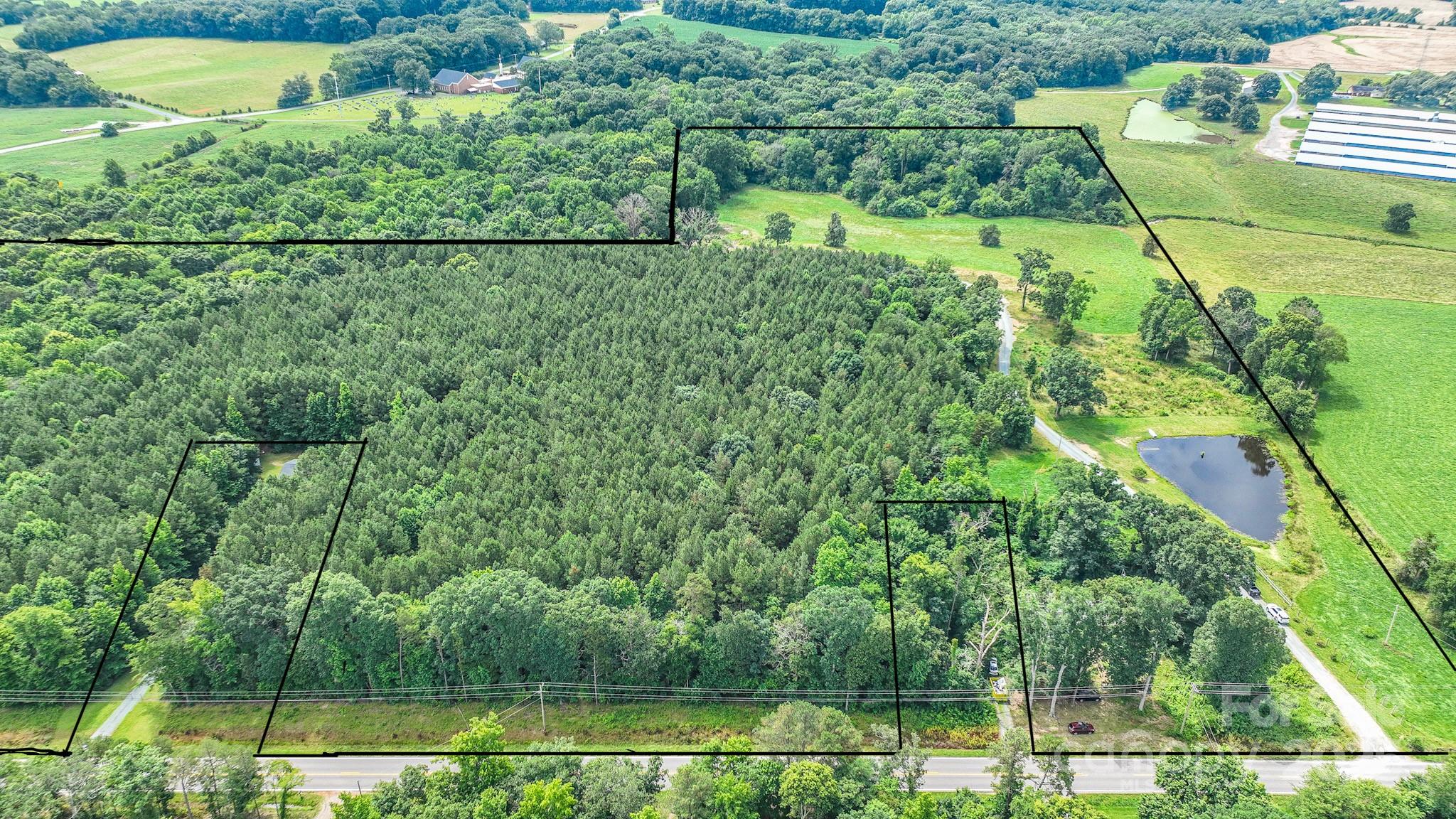 Rare opportunity to own approx. 30 acres in Waxhaw with excellent road frontage along Lancaster Hwy. This beautiful property includes two parcels 04312027A & 04309006R being sold together with a perfect mix of cleared and wooded land. A peaceful pond welcomes you at the entrance, with a private driveway leading to the middle of the property where a large barn sits offering endless potential. Roughly half the acreage is cleared, while the rest features mature pine trees and natural privacy. A small creek runs along the back of the property with a bridge allowing access to the other side—perfect for exploring, riding, or future use. Whether you’re planning to build a private estate, family compound, horse facility, event venue, or neighborhood this land offers endless possibilities. The property previously perked for septic, though the permit has expired. With usable land, scenic views, and high visibility, this is an ideal setting for residential, recreational, or investment use.