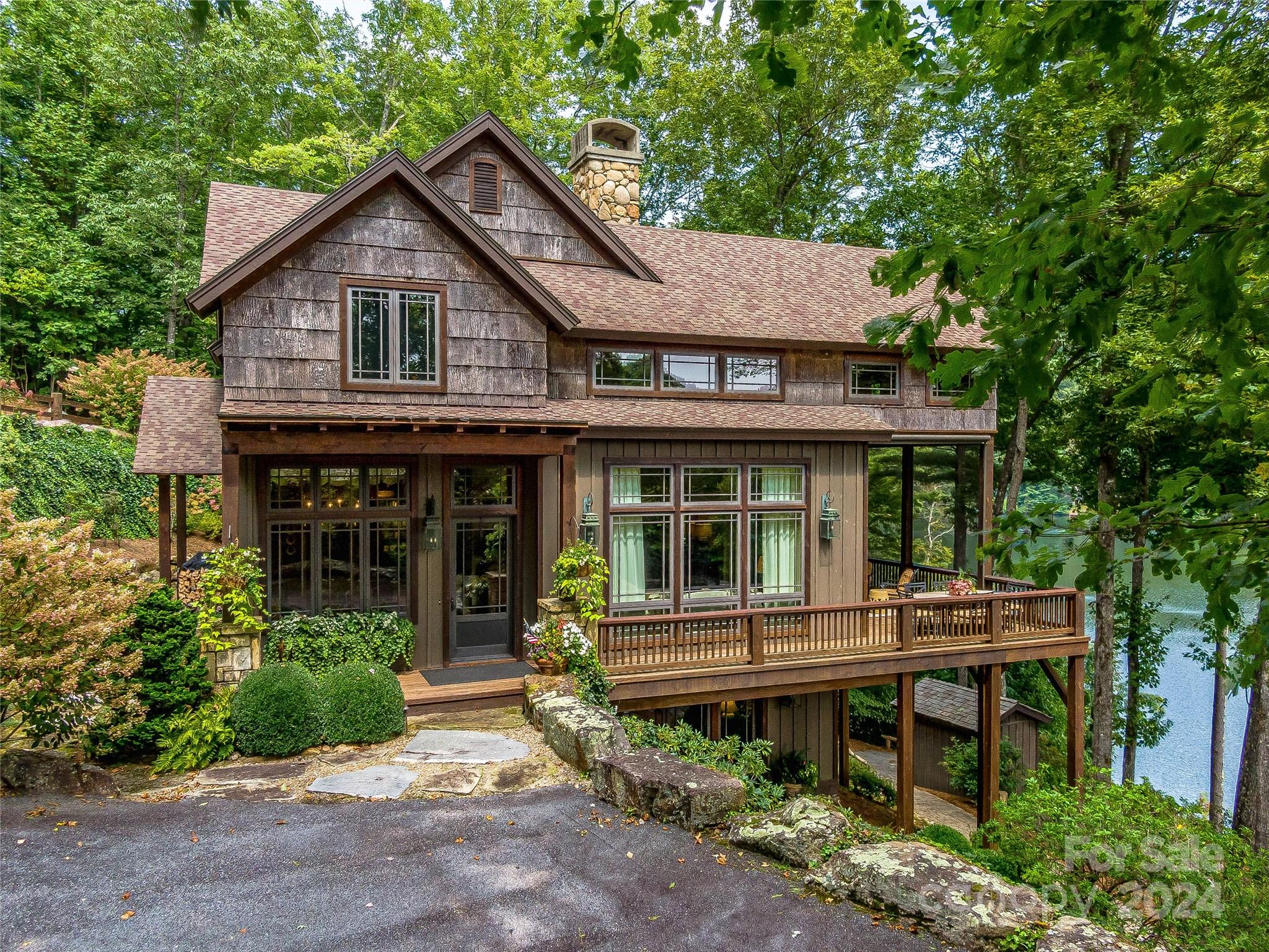 This stunning Arts & Crafts-style home on Lake Cardinal offers lake views and easy access to fun on the water. Enjoy cruising through the Estates on your golf cart included with the property, and store it in your custom-built cart shed. A John boat with a lithium-ion motor, kayaks, and a canoe are also included in the purchase. A stone path leads down to the water, your private dock, and water sport storage. Native landscaping and a screened porch with a retractable side opening to the deck allow for additional outdoor enjoyment. Inside the home, Heart Pine floors add warmth and character. Cozy up by the massive stone fireplace in the main living area while gazing through large windows showcasing picturesque lake views. The gourmet kitchen boasts Wolf and Subzero appliances, complemented by granite countertops and a hammered copper farmhouse sink. Comfortably entertain friends and family in this lakeside retreat.