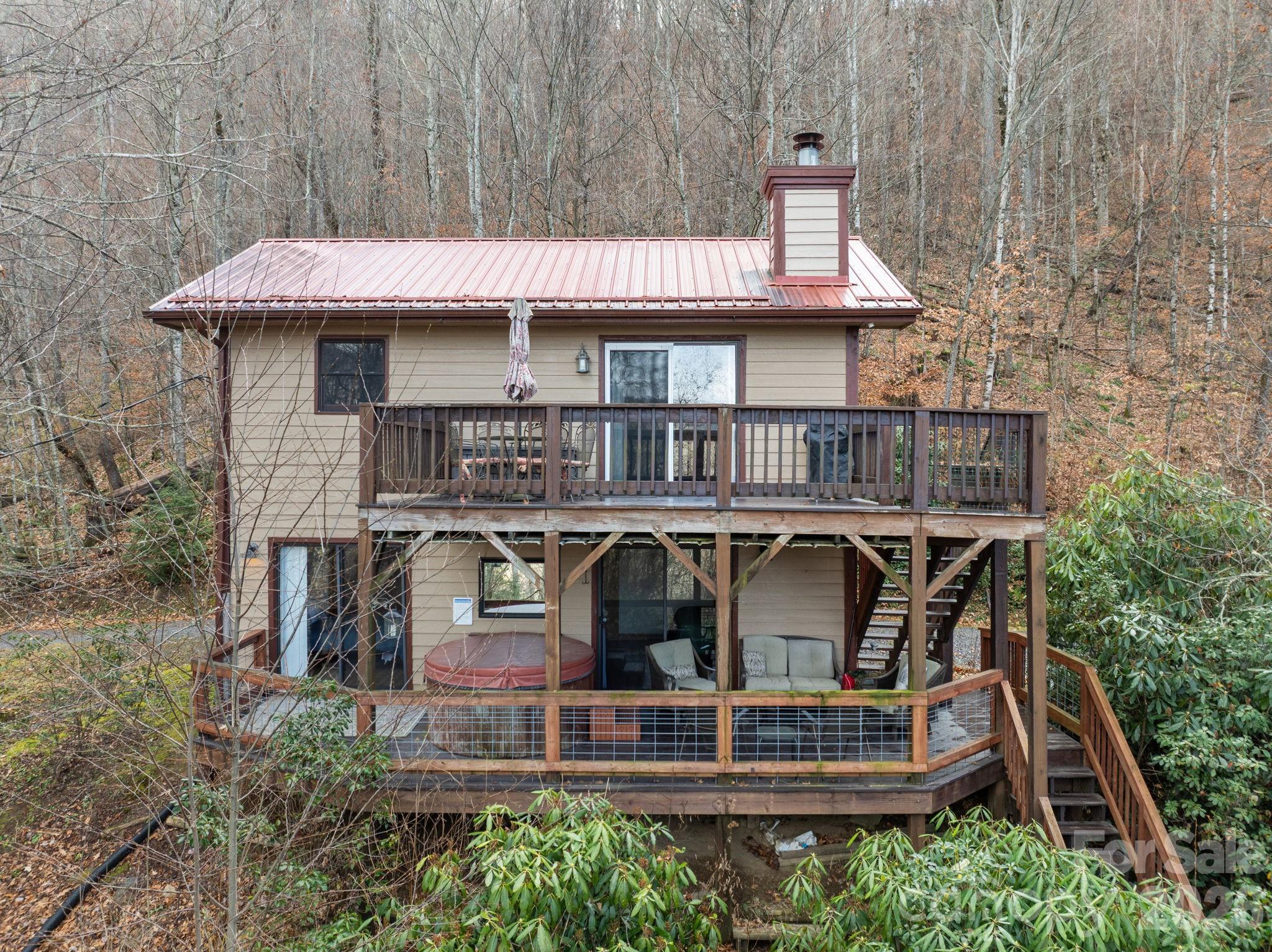 Live on permanent vacation at 4,300 ft with sweeping, multi-layered Blue Ridge Mountain views that change like a postcard every day. This 2 bedroom, 2 bath mountain charmer sits on almost an acre, just minutes from the Blue Ridge Parkway and downtown Maggie Valley, yet feels gloriously secluded. Walk in on the main level to two bedrooms with direct access to the lower deck and bubbling hot tub, pure bliss under the stars. Upstairs you are greeted with vaulted tongue-and-groove ceilings, stainless appliances, and walls of windows framing the endless views while you sip coffee or gather around the fire. The exterior of this mountain get away offers a circular driveway, well-maintained gravel road, treehouse, playground, and added storage in the shed that is equipped with power. If you're looking for cool summer breezes, fiery fall colors or snowy winter peaks, this property has them all year-round! At 959 Plott Balsam, every day feels like you’ve escaped to the mountains… because you have. And you will never want to leave!
