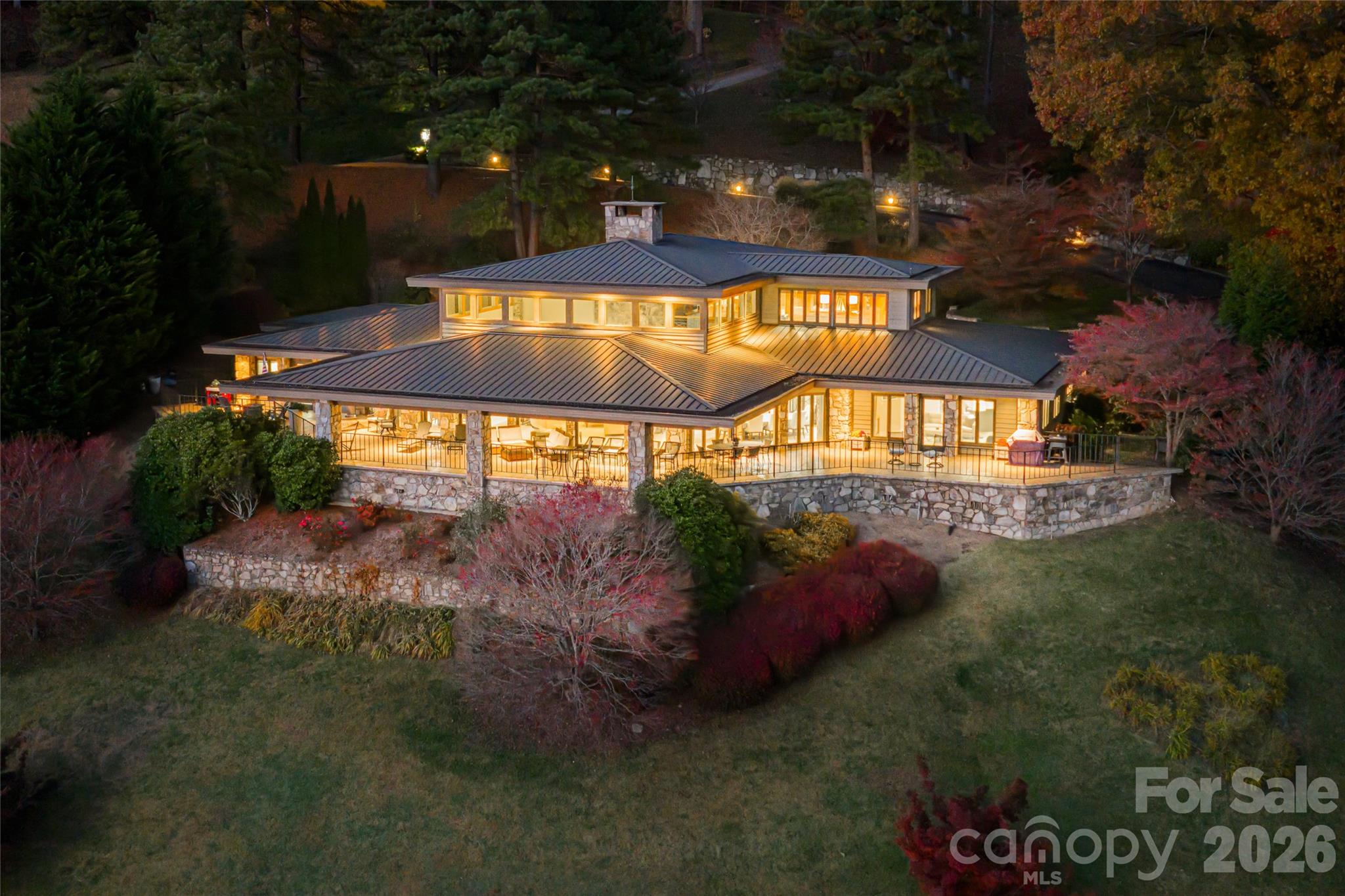 Architectural artistry and refined mountain living come together above the most scenic green at Laurel Ridge Country Club. Positioned over the 11th tee with panoramic mountain, golf-course, and valley views, this contemporary residence offers one of the most striking vantage points in Waynesville. Originally inspired by the Frank Lloyd Wright style, the home was re-envisioned in 2008 to honor clean lines, natural materials, and seamless connection to the outdoors while adding modern comfort and function.

Walls of glass pull the landscape inward, filling the great room with natural light and framing the Blue Ridge like living art. A soaring ceiling, floor-to-ceiling stone fireplace, and striking architectural details create a space that feels both dramatic and deeply welcoming. Just beyond, a wide wrap-around veranda spans the length of the home—an unforgettable outdoor living environment for sunset dinners, weekend entertaining, and quiet mornings overlooking the fairway and long-range ridgelines.

Designed for effortless main-level living, the primary suite provides a peaceful retreat with an adjoining bonus room currently used as a home gym. This space adapts beautifully as a private office, sitting room, Hollywood-style dressing room, or the footprint for a second spa-like bath. The kitchen is supported by both a butler’s pantry and a separate walk-in pantry, ideal for everyday life and elevated entertaining. A distinct everyday entrance and separate guest entrance add sophistication to the home’s sense of arrival.

The upper level functions as a private guest wing with a second primary suite, a large loft, an office, and another ensuite guest room—perfect for extended stays and hosting with ease. Fully zoned HVAC, ample basement storage, an oversized two-car garage, a brick-paver driveway, and extensive exterior lighting reflect thoughtful planning inside and out.

All of this awaits just minutes from historic downtown Waynesville, known for boutique shops, fine dining, galleries, and year-round festivals—and only about 30 minutes from Asheville, a nationally regarded destination for arts, culture, and acclaimed restaurants.  A rare opportunity to own a luxury residence with sweeping mountain and golf-course views, timeless architecture, and one of the most inviting outdoor living spaces in Western North Carolina.