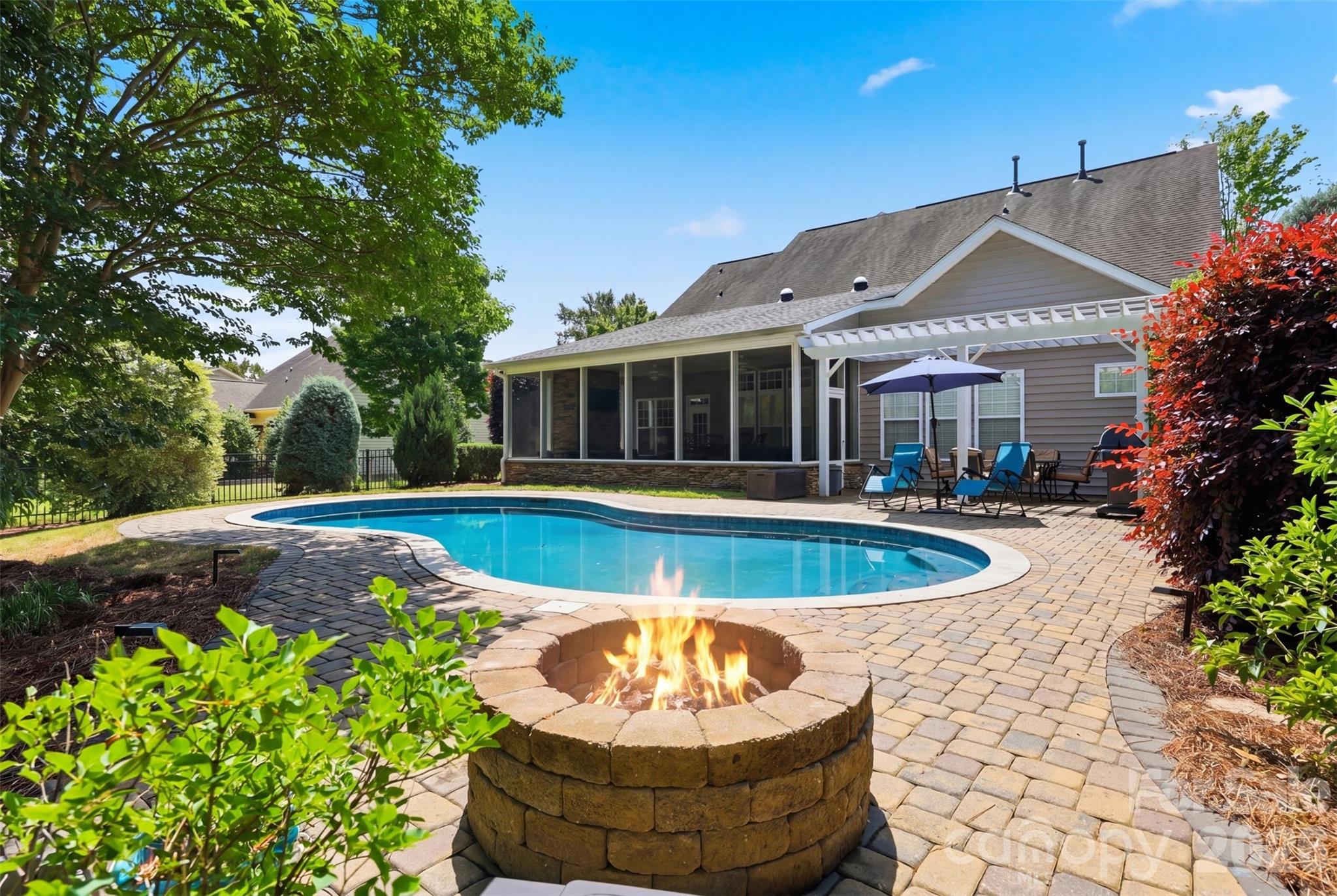 This stunning, move-in ready gem offers the perfect blend of comfort, style, and functionality.
The main level is designed for both relaxed living and effortless entertaining, featuring a private primary suite, soaring two-story family room with a cozy gas fireplace, separate dining room, and a half bath. The chef-inspired kitchen is sure to impress with granite countertops, tile floors and backsplash, double oven, walk-in pantry, and a built-in desk area — all open to the family room, keeping everyone connected.
Upstairs offers three spacious bedrooms, a large sitting area perfect for a bonus room/home office/playroom, plus two full baths. Fresh, neutral paint throughout 80% of the home means you can move right in and make it your own.
But the real showstopper? The backyard. Dive into your own private saltwater pool, unwind in the expansive screened room with plenty of room for seating around the gas fireplace, lounge around the firepit or simply enjoy the serenity of a fully fenced, level yard surrounded by mature trees and a green space to the right. Outdoor living doesn't get better than this.
Beyond your doorstep, the neighborhood delivers fantastic amenities — a large outdoor pool, clubhouse, playground, airnasium and pickleball court — all with sidewalks, street lighting, walking trails, and two convenient entry points.  And it's located in the highly coveted Fort Mill School District (PKMS is currently under an enrollment freeze. Please verify school assignments directly with Fort Mill School District).