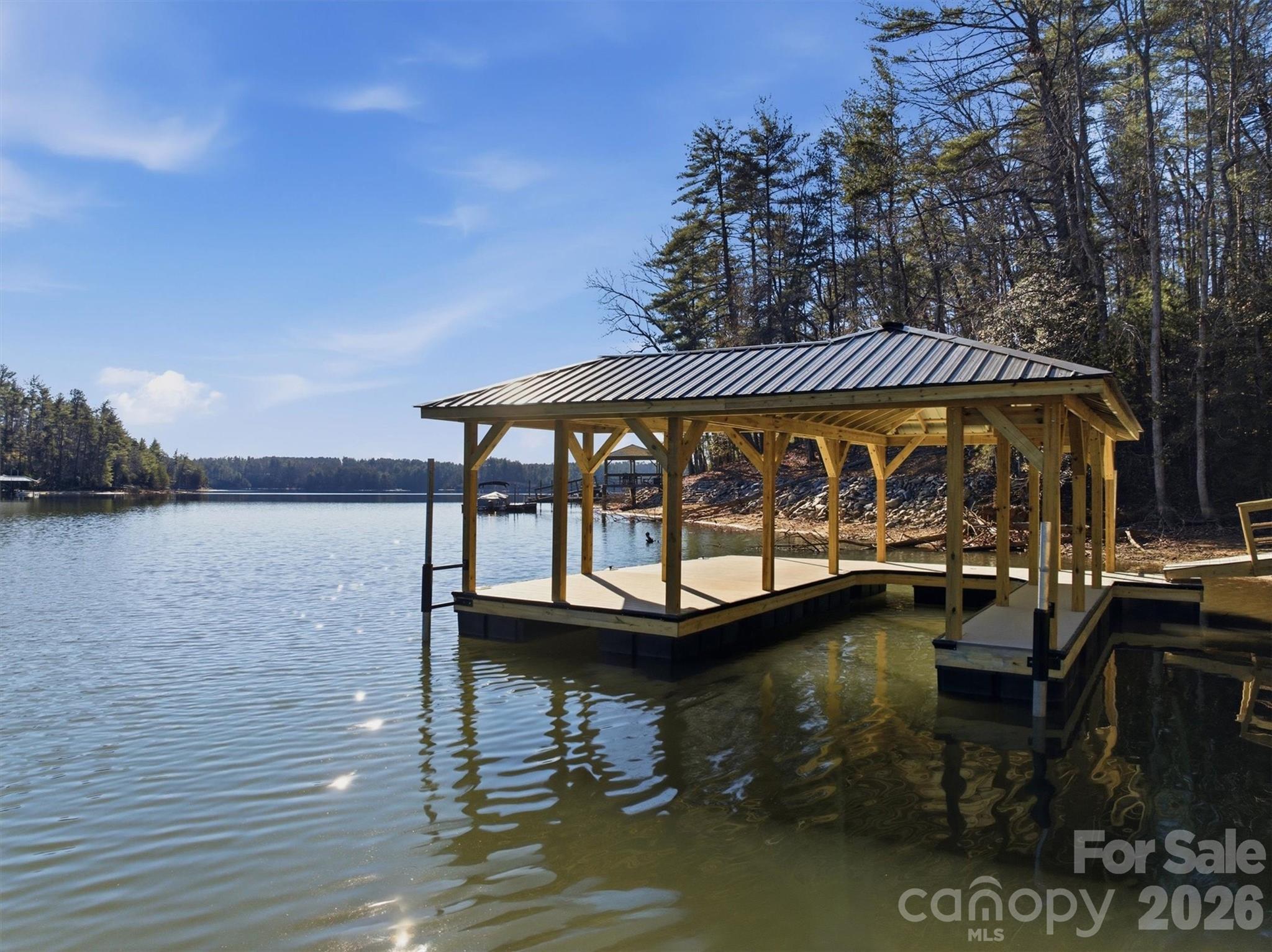 This successful short term rental is being offered turn-key and furnished. Brand new dock has been installed, enhancing an owner's enjoyment of the private beach. Open, airy, and bright waterfront home with rustic charm located in renowned 1780 on Lake James. Known affectionately as Kingfisher to the many vacationers that choose this beautiful getaway every year, . On the main floor you'll find the large but cozy family room with vaulted ceilings and dramatic stone fireplace. The ample kitchen, walk-in pantry, and dining room are adjoining with access to the large back deck and screened in porch. The laundry and spacious primary suite with access to the screened porch and outside fireplace are also located on the main floor. The lower level includes a second full suite, 2 additional large bedrooms, 2 full and 1 half baths, a bunk room with 4 built-in bunk beds, rec room, mud room, additional laundry, and UTV garage. Camp Lake James membership included!
