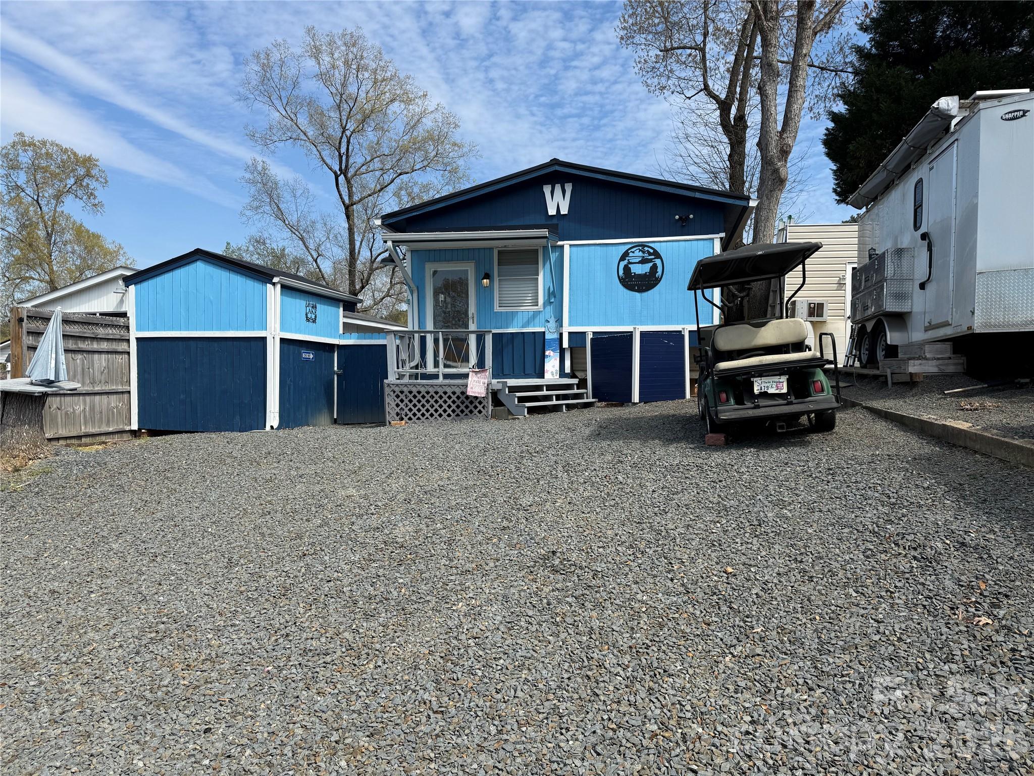 Welcome to this unique unit here in the park. This a 2 bedroom, 2 1/2 baths unit with a fabulous outdoor kitchen setup and a second sleeping/bathroom space. Included in the outdoor kitchen -  Blackstone Gas Griddle, Blackstone Prep Area, covered with elec and fan. Move over to the covered bar side and you have 4 stools, a beverage refrigerator, Microwave, Ninja Foodie Grill, Panini Maker, Oster French Door Oven. Power and a TV are already there. There is a covered swing, fenced yard for the pets and a pet washing station. Inside is a great living room freshly painted with new flooring. Most furnishing to remain. U shaped couch makes a comfortable queen bed. The kitchen has an ice maker, great counter space and brand new flooring. Metal roof is 1 year old. Propane Hot Water on Demand 2 years old. 2 Window units for AC and a wall mounted propane heater for your heat source. Access door just added to the side of unit for the convenience of letting the dogs out into the fenced area. Full bath with walk in shower. Storage or Sleeping loft above main bath room. Double size bed and 1/2 bath on the camper side. Out back is double bunks, a full bath and enough room to add a washer and dryer if desired. Portable A/C and fan.
Come and see if this is your "Happy Place" here in the Park. No title to camper, Bill of Sale will be provided. 
There are 2 Yamaha 2011 golf carts available for Alum wheels $4k, black wheels $3k. 
All buyers must be with a realtor to gain access to the community.