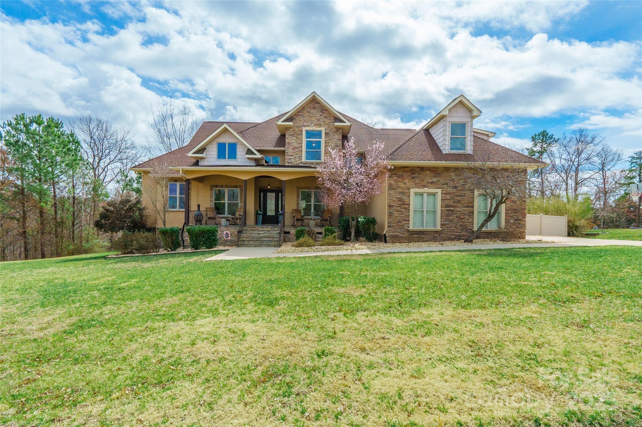 Exceptionally stunning home with convenient access to Lake Wylie, located in the Clover School District with 4 bedrooms! This beautiful home sits on a one-acre wooded lot in a lakeside neighborhood with no HOA fees. The oversized rocking chair front porch leads to a space with hardwood floors, a stone fireplace, 18’ ceilings, and built-ins. Sliding doors open to a veranda spanning the great room, breakfast nook, and primary bedroom. The gourmet kitchen features granite countertops, soft-close cabinets, induction cooktop, and under-cabinet lighting. Upstairs, enjoy two generous bedrooms and a bonus room/bedroom with a walk-in closet, private bath, and built-in bar with a mini fridge, sink, cabinets, and granite countertops. Outdoors, relax in the custom-built 15,000-gallon shotcrete saltwater pool with a sundeck, plus a two-tiered screened deck with a ceiling-mounted screen. This immaculate home has it all! See the attached write-up for full details!