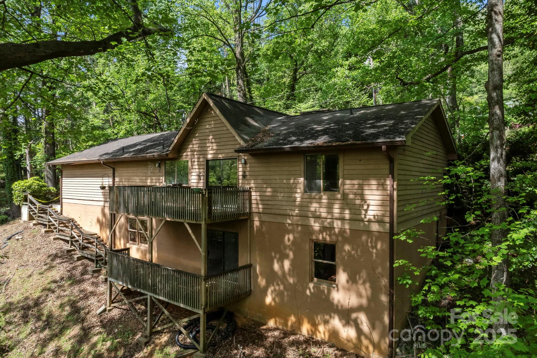Calling all dreamers—this well-loved home is bursting with potential and ready for a fresh start! Completely livable as is, while you do updates to make it your own. Tucked away in the trees just 2 miles from downtown Tryon’s charming shops, dining, and culture, this elevated ranch offers privacy and convenience. The main level features soaring cathedral ceilings, a dramatic floor-to-ceiling fireplace, and large kitchen windows with natural light flooding in. A split bedroom layout includes three bedrooms, two full baths, and a laundry room, making for easy one-level living. Downstairs, the massive unfinished basement with tall ceilings, a brick fireplace, and an existing full bath opens the door to endless possibilities—create additional living space, a studio, or an in-law suite. A 2-car garage and generous paved driveway add practicality and ease. Bring your vision—this home has great bones and the space to become something truly special. DO NOT WALK ON THE REAR DECKS!