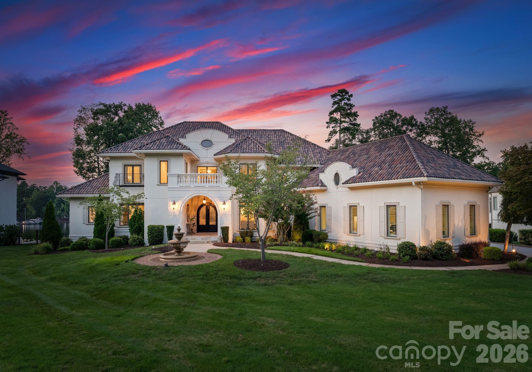 Welcome to "Villa Bianca," an extraordinary waterfront estate nestled within The Point on Lake Norman. Set on nearly an acre with sweeping, year-round water and golf course views, this timeless white-stucco residence makes an unforgettable first impression from the moment you arrive. Inside, soaring ceilings, refined architectural details, and beautifully curated finishes create an atmosphere of effortless elegance. The primary suite is conveniently located on the main level, offering a serene retreat with spa-like comforts. At the heart of the home, a true chef’s kitchen features custom cabinetry, an oversized island, and top-of-the-line appliances—seamlessly flowing into expansive living and dining spaces designed for both everyday living and elevated entertaining. Upstairs, generously sized bedrooms, a private study, a cozy library, and a spacious bonus room provide flexibility and comfort. The fully finished walk-out basement is an entertainer’s dream, complete with a second full kitchen, recreation and living areas, and a home theater—perfect for hosting guests or creating a private retreat. Step outside to your own resort-style escape, where breathtaking sunsets frame Lake Norman and the surrounding golf course. Enjoy the in-ground pool and spa, multiple outdoor living spaces, and a private dock with boat lift, offering effortless access to lake life at its finest. Located in one of Lake Norman’s most coveted communities, residents of The Point enjoy world-class amenities including golf, tennis, fitness, walking trails, and lake access—just minutes from dining, shopping, and Charlotte. A rare offering of timeless architecture, refined luxury, and unmatched lifestyle—Villa Bianca is truly one of one.