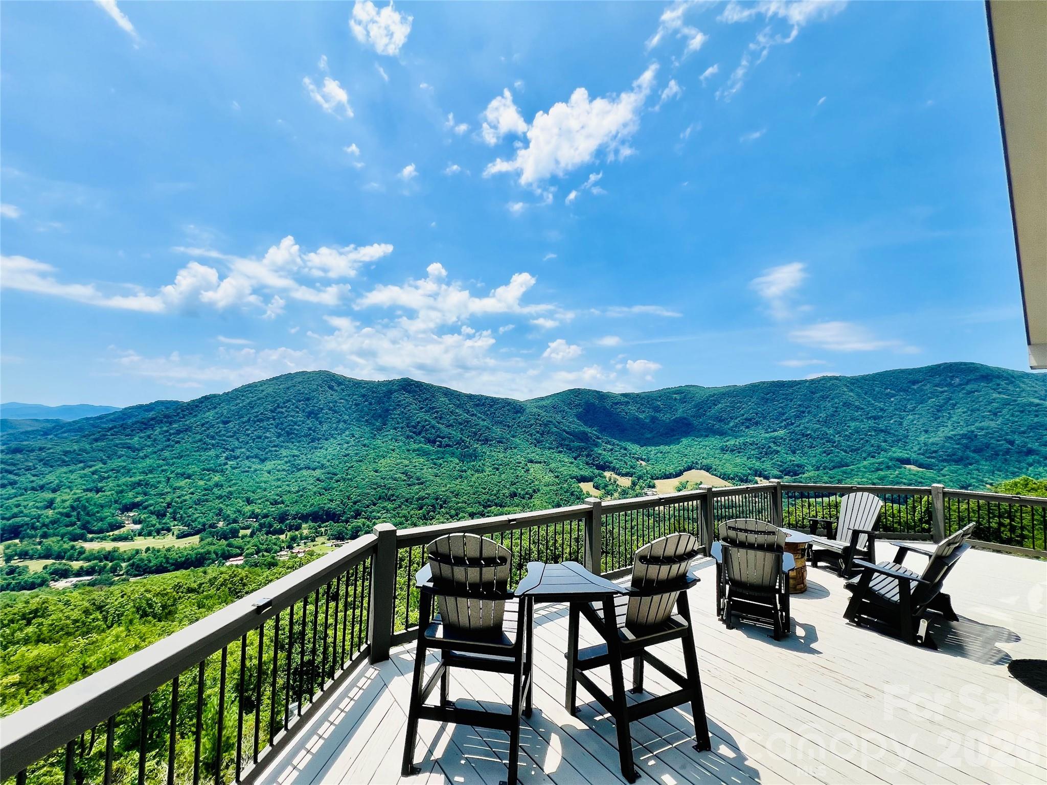 There are mountain homes… and then there are mountain experiences!
Perched high above the valley floor on 5.59 private acres and bordering Pisgah National Forest, this stunning retreat captures the kind of long range Blue Ridge Mountain views that people spend years searching for and rarely find. With protected forestland as your neighbor and breathtaking mountain vistas stretching to the horizon, you’ll enjoy a rare combination of privacy, natural beauty, and an unparalleled connection to the outdoors.
From sunrise over the ridgelines to evenings gathered around the fire table beneath a canopy of stars, every inch of this property was designed to showcase the view.
The main level welcomes you with soaring ceilings, a wall of windows, rich wood finishes, and an open-concept living area anchored by a stone fireplace. The mountains become part of the décor, filling the home with a constantly changing backdrop that can be enjoyed from nearly every gathering space. Comfort is enhanced year round by a highly efficient 4-zone heat pump system, allowing customized climate control throughout the home.
Step outside to expansive covered and open air decking  (approx 1800 sq ft) where you’ll find multiple areas for dining, entertaining, relaxing, and taking in the breathtaking scenery. Whether you’re soaking in the hot tub, sharing a bottle of wine by the fire pit, or enjoying coffee on the porch, the view is always center stage.
Offering 5 functioning bedrooms, 3 full baths, and three levels of living space, the home comfortably accommodates family and guests. (Septic permit is for 4 bedrooms.) The lower level recreation room creates the perfect gathering spot for game nights and mountain getaways, while the private upper level primary suite offers a peaceful retreat at the end of the day. Lower level is also plumbed for another kitchen for added expansion opportunities! 
For investors and second home buyers alike, the property also boasts an impressive vacation rental history, making it an exceptional opportunity to enjoy the mountain lifestyle while generating income. Offered fully furnished, this is a rare turnkey opportunity. Simply arrive, unpack, and start enjoying the views. Adding even more value, an additional lot conveys with the property and already has electric service and a transformer in place, providing a rare opportunity for a future guest house, second residence, or expanded family compound.
With 5.59 acres, direct adjacency to Pisgah National Forest, expansive outdoor living spaces and views that simply cannot be replicated, this is more than a mountain home… it’s a MOUNTAIN DESTINATION.
The home is exceptional. The setting is unforgettable. The view is why you’ll never want to leave.