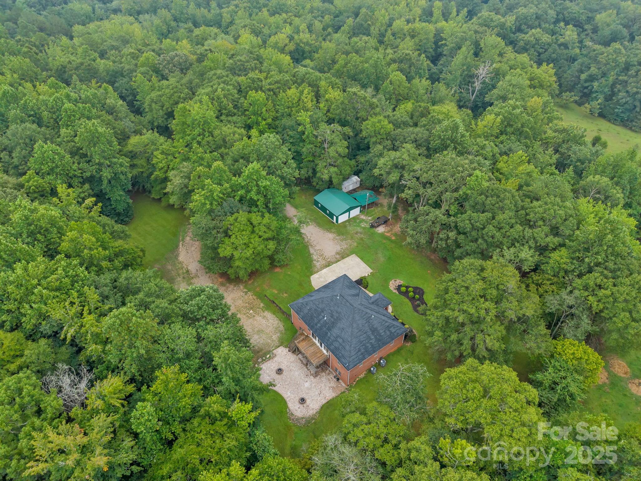 Nestled on 26 serene, wooded fenced acres, this charming brick residence offers privacy and multiple possibilities.  The home itself sits in the center of  the property and is fenced in from rest of acreage. On the main floor, you’ll find 4 beds & 3 full baths, all within a bright, open floor plan featuring  a living area w/ custom built-ins, study/sitting room, formal dining rm, & an open kitchen—perfect for both daily living & entertaining. A lovely lanai and large deck to enjoy outside.   The fully finished basement is designed as the ultimate gathering space w/ a custom bar, expansive entertainment area, bath, & plenty of room for games,relaxation, seperate living quarters, storage  or even a small business. Off the basement is a large paver patio with two stone  firepits.  A new (2024) architectural shingle roof, spring water & whole-house generator provide both style and peace of mind. Outbuilding is 36x38-heated/cooled, water and 200amp electric for parking, storage or workshop.