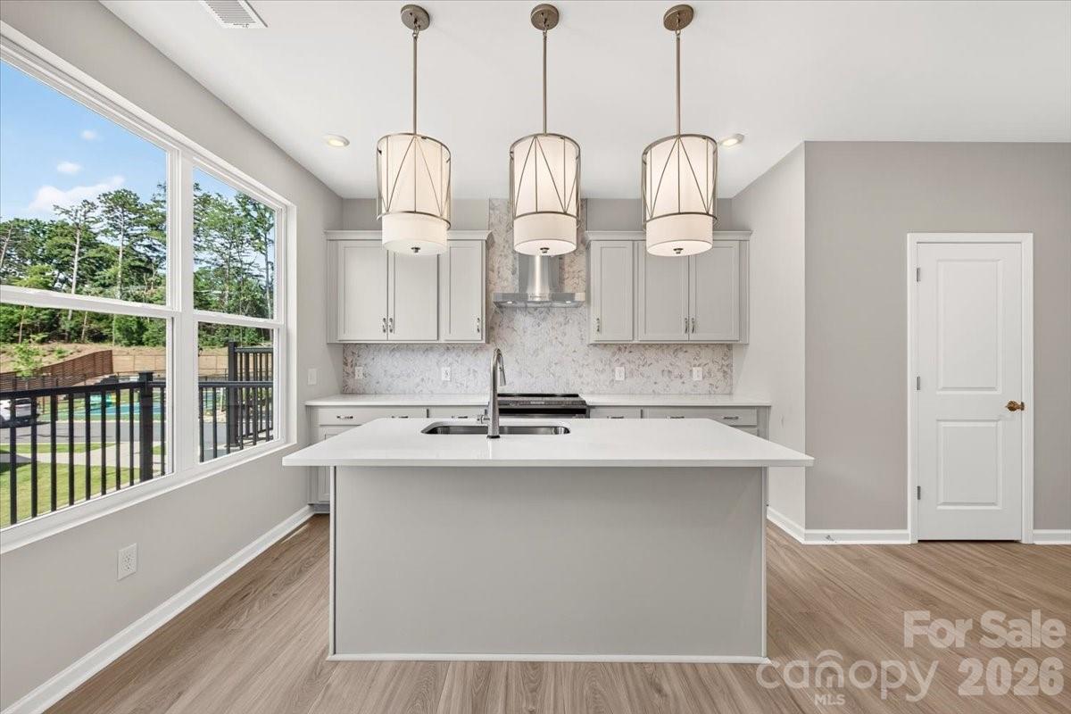 Welcome to 5513 Swaling St, a Collins plan townhome within the gated Southmont community in Charlotte, NC. This low-maintenance 2-bedroom, 2.5-bathroom home offers 1,408 sq ft of thoughtfully designed living space across three floors, complete with a 2-bay tandem garage. Oak box stairs welcome you in and lead to the heart of the home on the second floor, where an open-concept layout brings together the gourmet kitchen, dining space, and living room, all with access to a balcony for seamless indoor-outdoor living. The kitchen is a true showstopper, featuring white cabinetry and white countertops paired with a Marble Obsession Arabescato picket mosaic backsplash, a large island with a single-bowl stainless steel sink and Delta Essa touch faucet, Kichler Birkleigh pendant lighting in satin nickel, and a GE Profile 30" electric range topped with a designer stainless steel hood. A powder room completes the second floor. Oak box stairs continue to the third floor, where the primary suite and secondary bedroom each feature their own private bathrooms. The primary bath is appointed with dual vanities, white cabinetry with a drawer bank, white quartz countertops, a tiled walk-in shower, and access to a generous walk-in closet. Gated entry, a pickleball court, and proximity to Southend, SouthPark, local dining, shops, and the light rail make Southmont a community worth calling home.