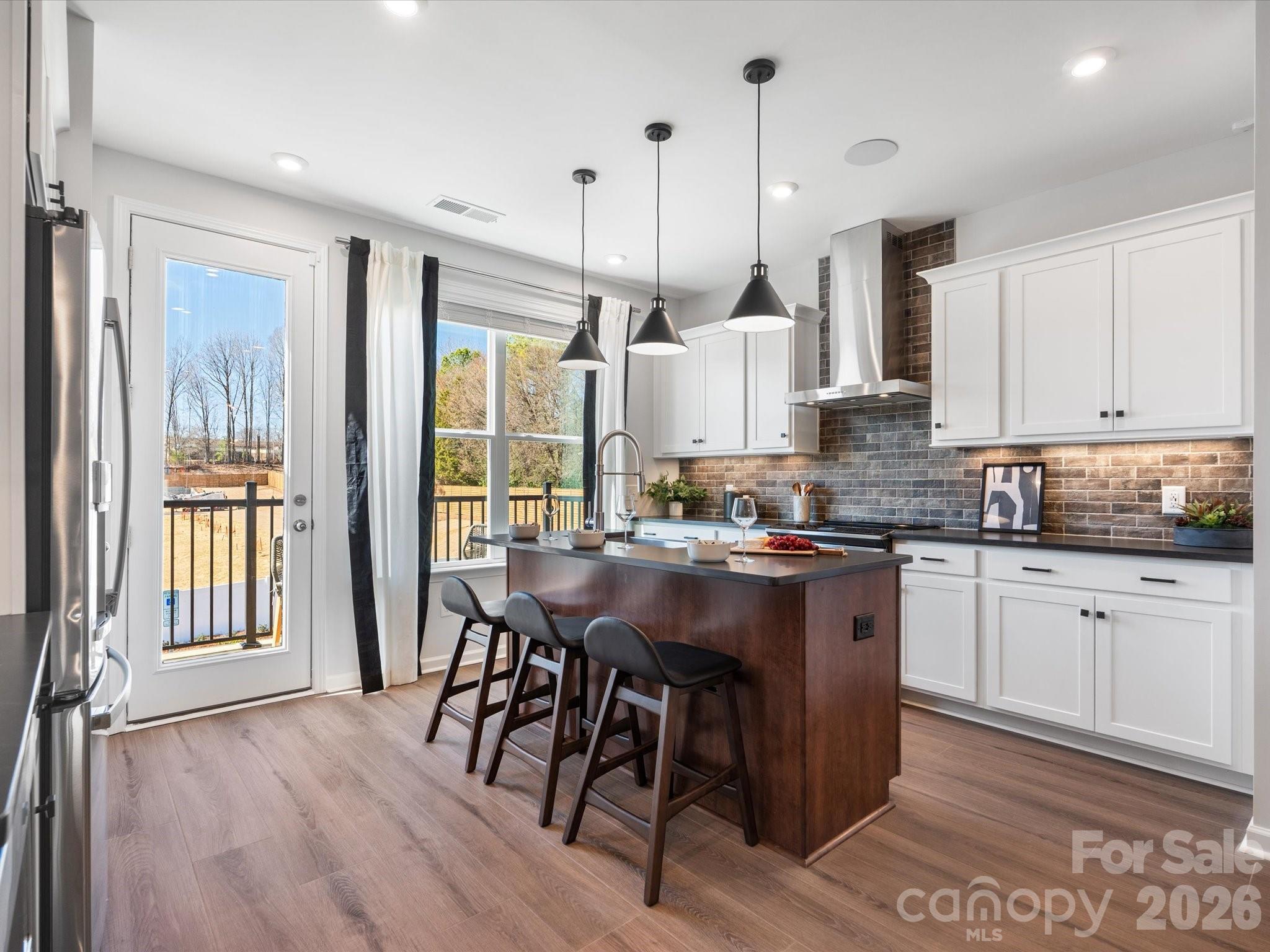 Welcome to 5513 Swaling St, a Collins plan townhome within the gated Southmont community in Charlotte, NC. This low-maintenance 2-bedroom, 2.5-bathroom home offers 1,408 sq ft of thoughtfully designed living space across three floors, complete with a 2-bay tandem garage. Oak box stairs welcome you in and lead to the heart of the home on the second floor, where an open-concept layout brings together the gourmet kitchen, dining space, and living room, all with access to a balcony for seamless indoor-outdoor living. The kitchen is a true showstopper, featuring white cabinetry and white countertops paired with a Marble Obsession Arabescato picket mosaic backsplash, a large island with a single-bowl stainless steel sink and Delta Essa touch faucet, Kichler Birkleigh pendant lighting in satin nickel, and a GE Profile 30" electric range topped with a designer stainless steel hood. A powder room completes the second floor. Oak box stairs continue to the third floor, where the primary suite and secondary bedroom each feature their own private bathrooms. The primary bath is appointed with dual vanities, white cabinetry with a drawer bank, white quartz countertops, a tiled walk-in shower, and access to a generous walk-in closet. Gated entry, a pickleball court, and proximity to Southend, SouthPark, local dining, shops, and the light rail make Southmont a community worth calling home.